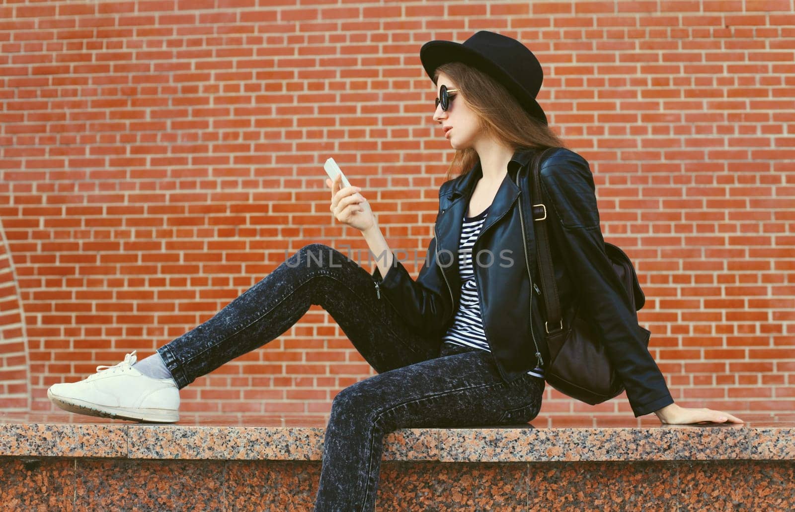 Modern caucasian young woman 20s model with mobile phone looking at device on city street