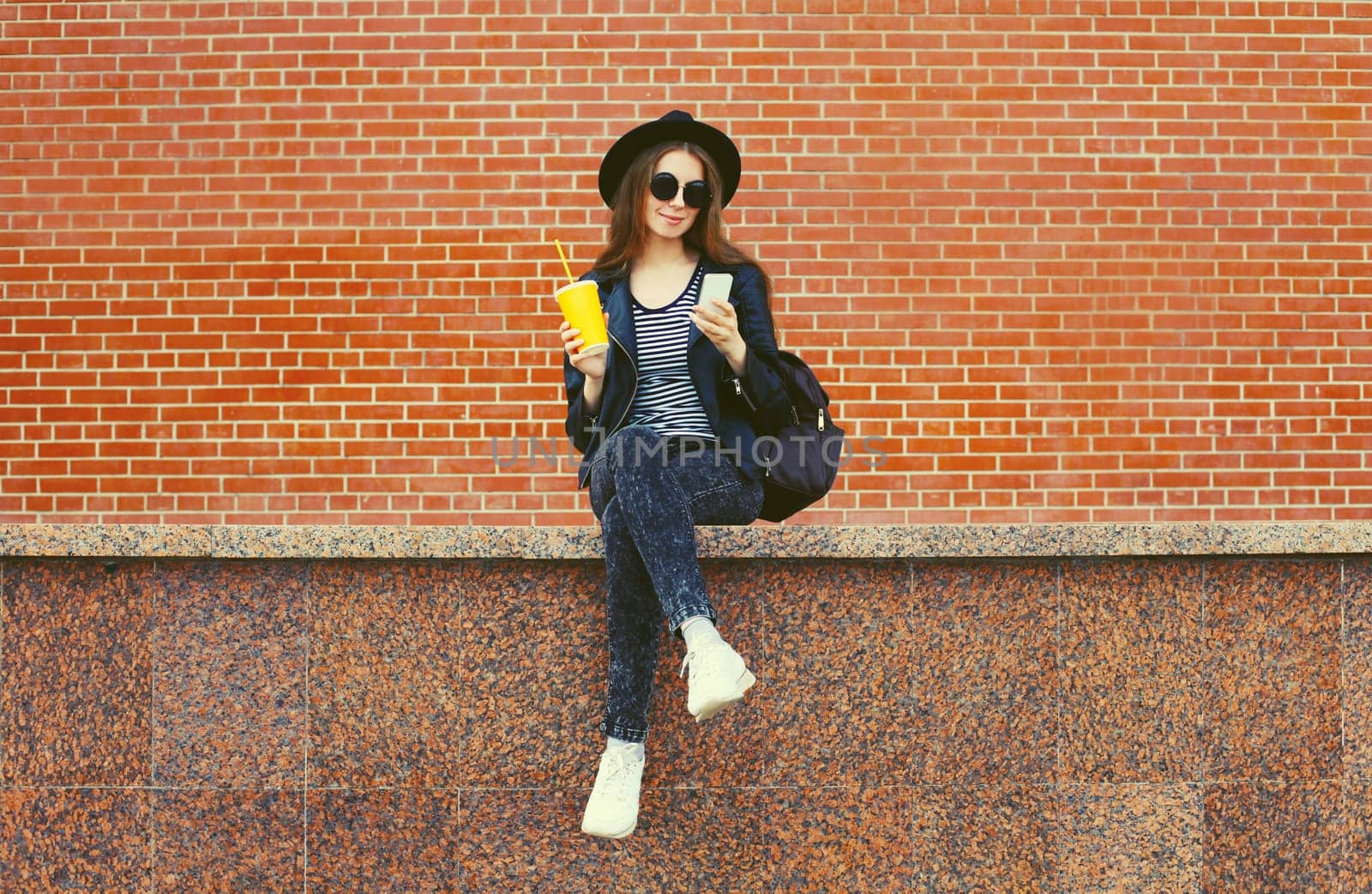 Modern caucasian young woman 20s model with mobile phone looking at device on city street