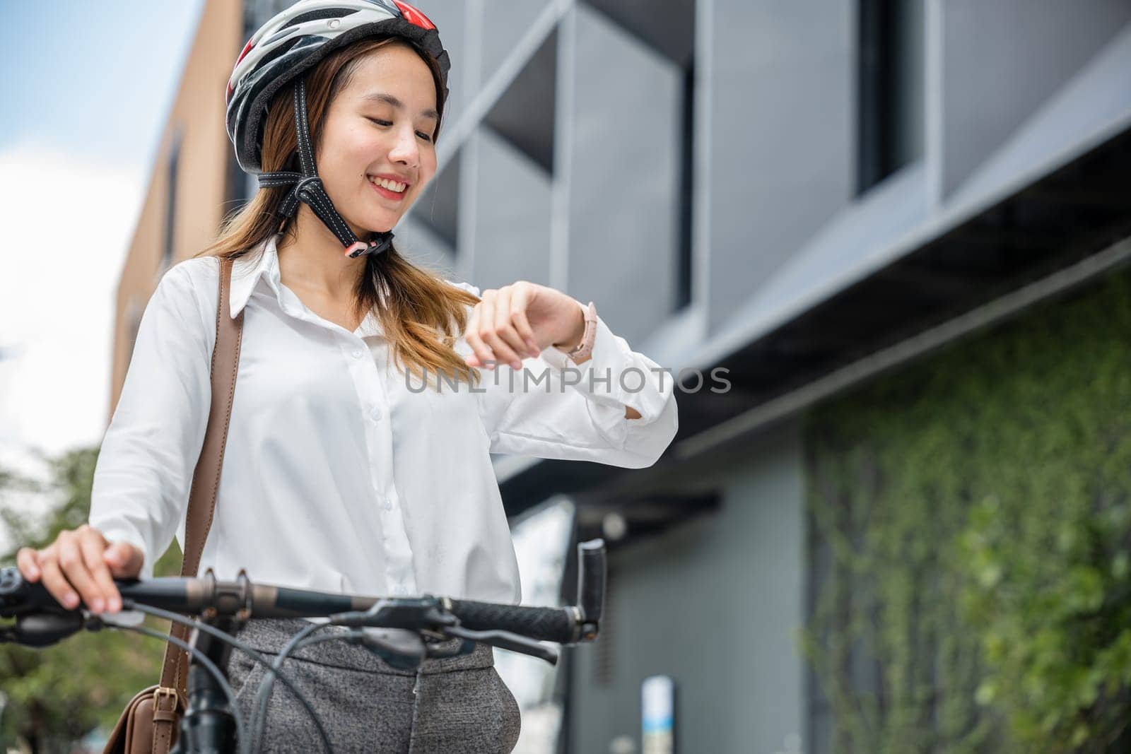 In the morning, a young businesswoman with a bicycle checks the time, embodying the lifestyle of a business commuter. Her professional look and helmet reflect her corporate profession.