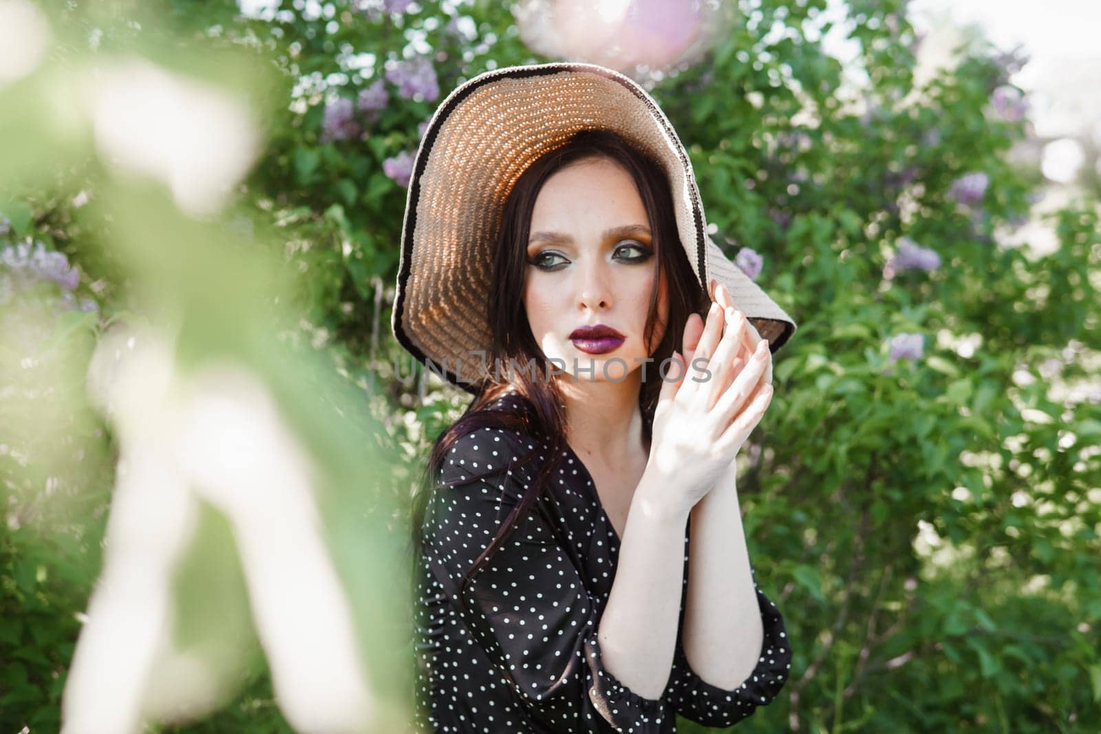 A fashionable girl with dark hair, a spring portrait in lilac tones in summer. Bright professional makeup