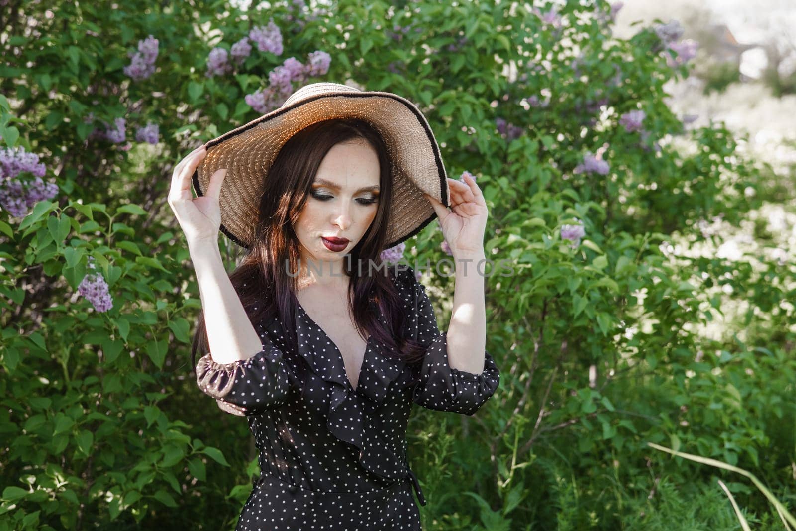 A fashionable girl with dark hair, a spring portrait in lilac tones in summer. Bright professional makeup