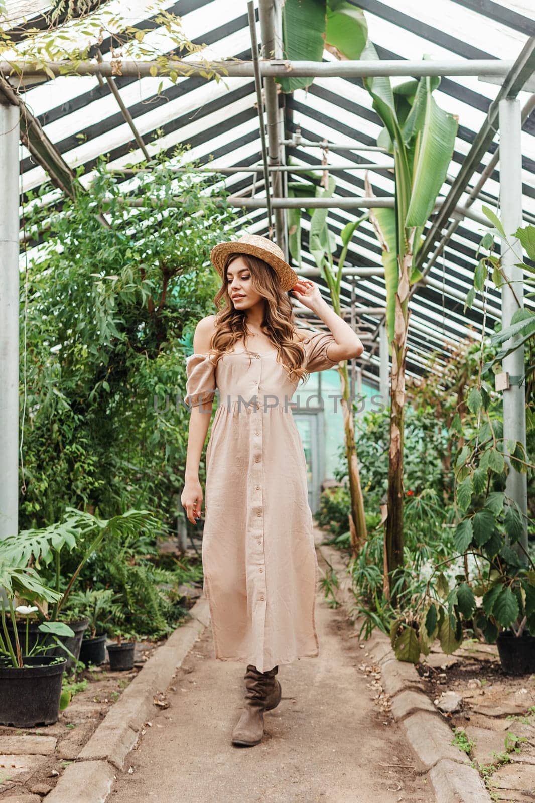 A beautiful young woman takes care of plants in a greenhouse. The concept of gardening and an eco-friendly lifestyle