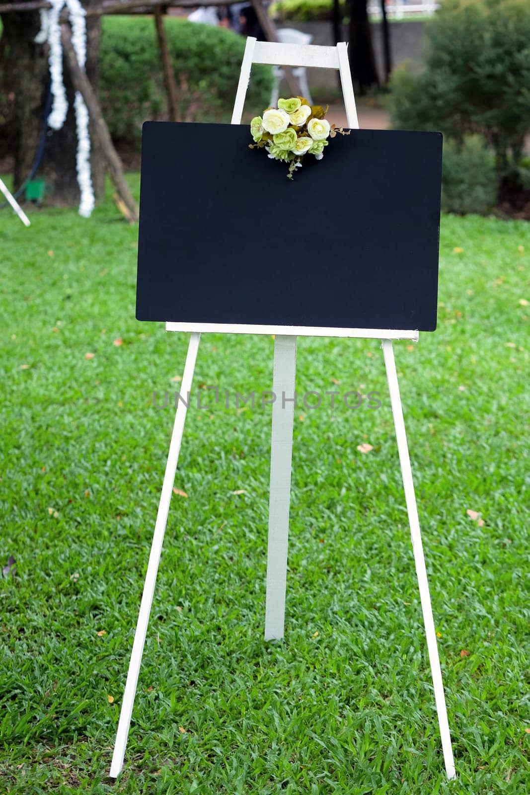 Blank black board with flower on the stand in the garden.