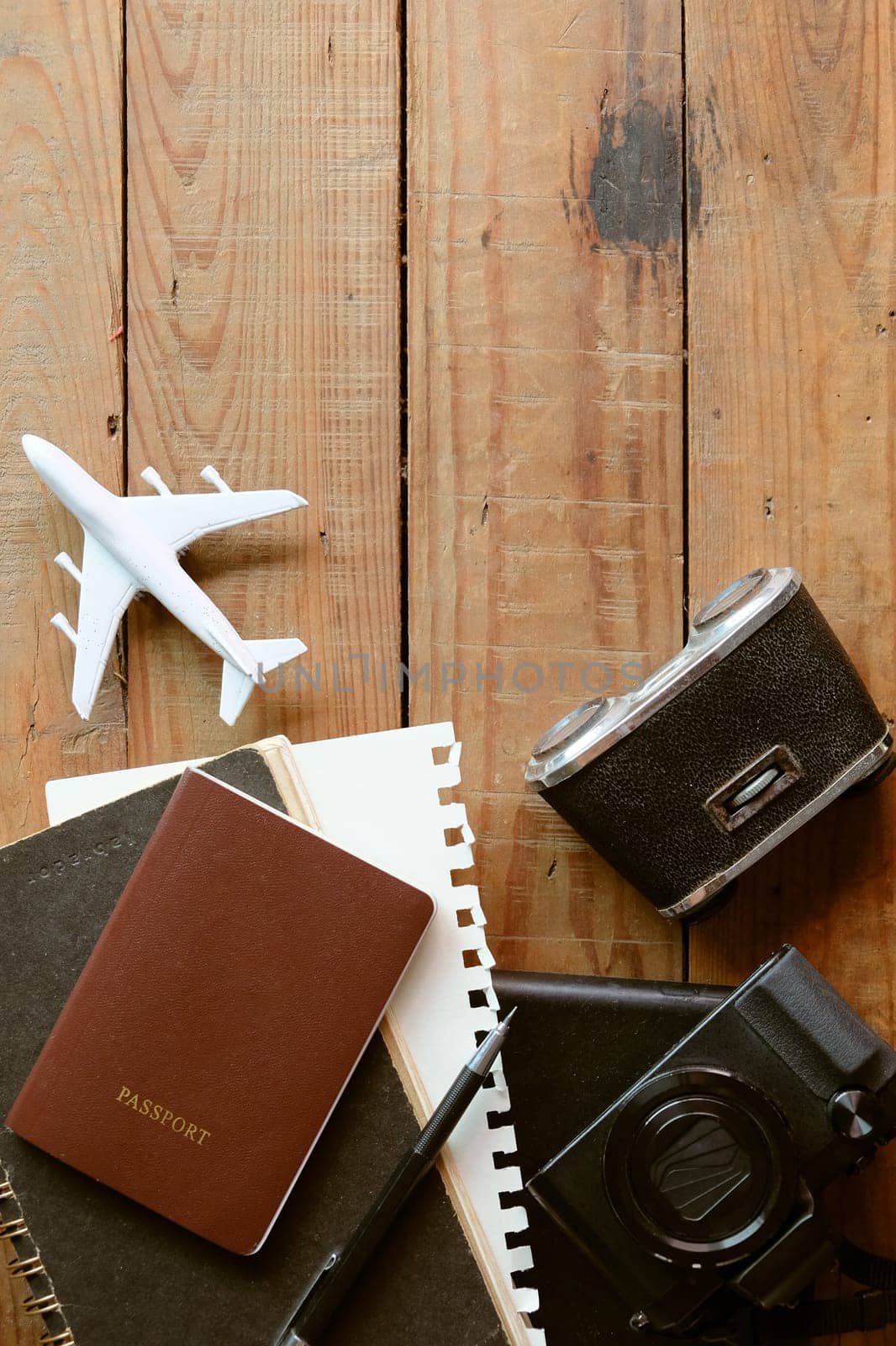 Travel concept with passport, camera, notebook and airplane on wooden background