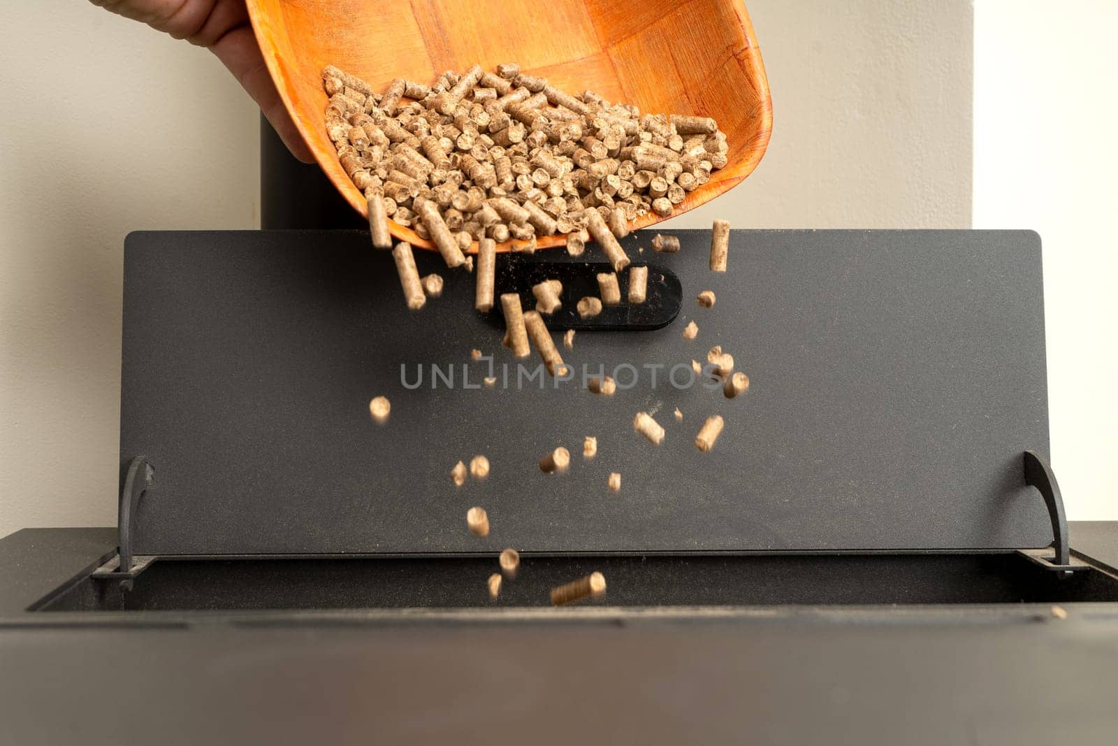 Closeup of a wooden basket filling a pellet stove. Sustainable and ecological heating.