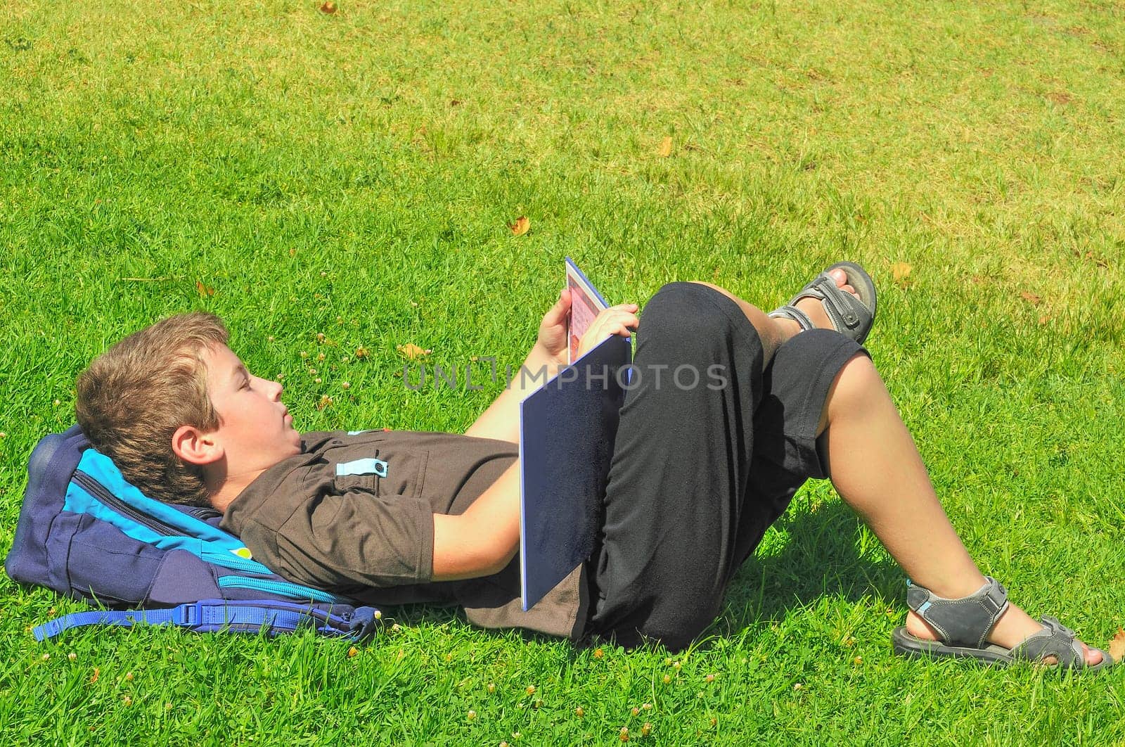 The boy, after school, lay on the grass and reading a book