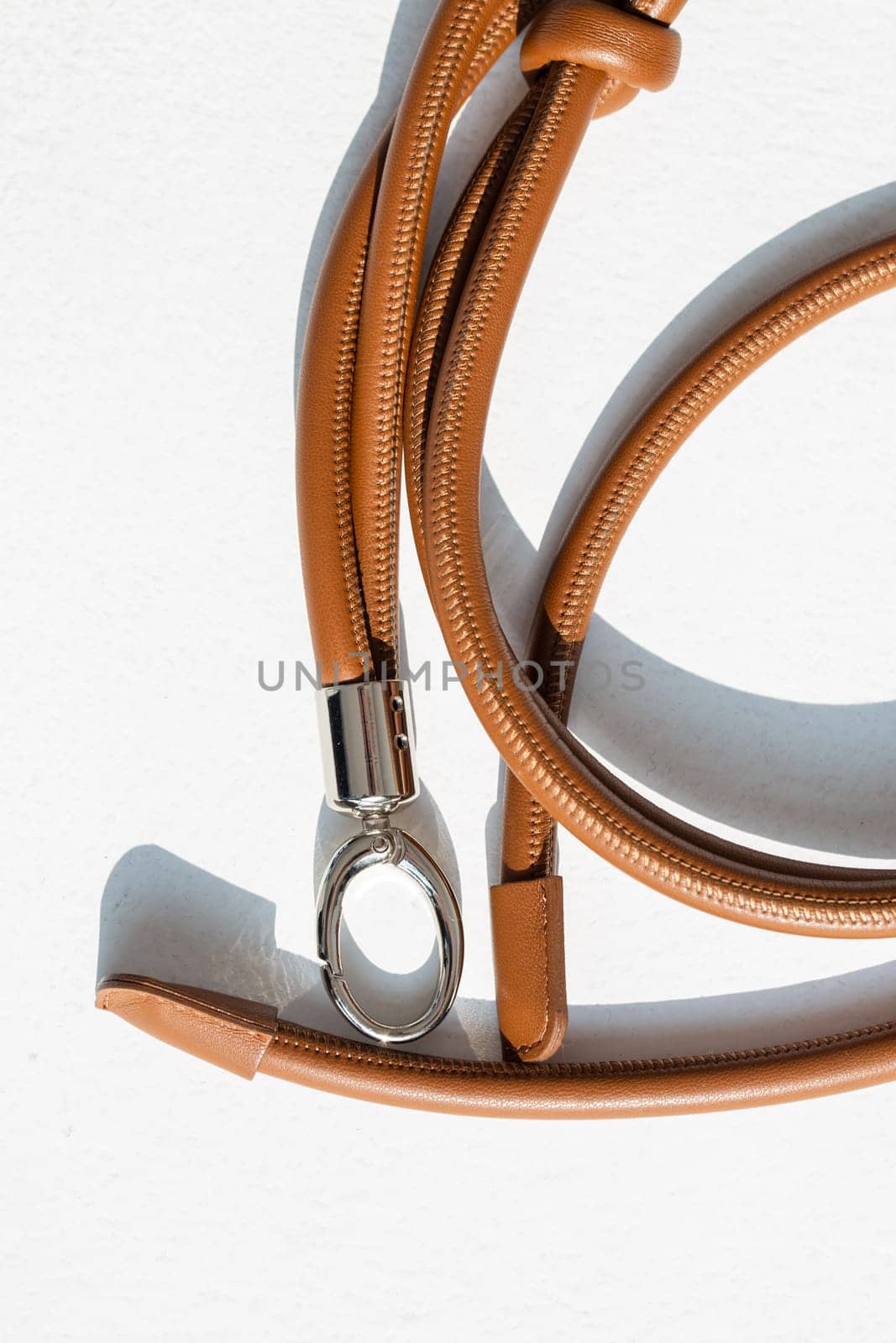 Brown genuine leather bag strap or handbag handle isolated on white background. High-quality material with a unique knot design adds style and elegance to your bag. Perfect accessory for any occasion.