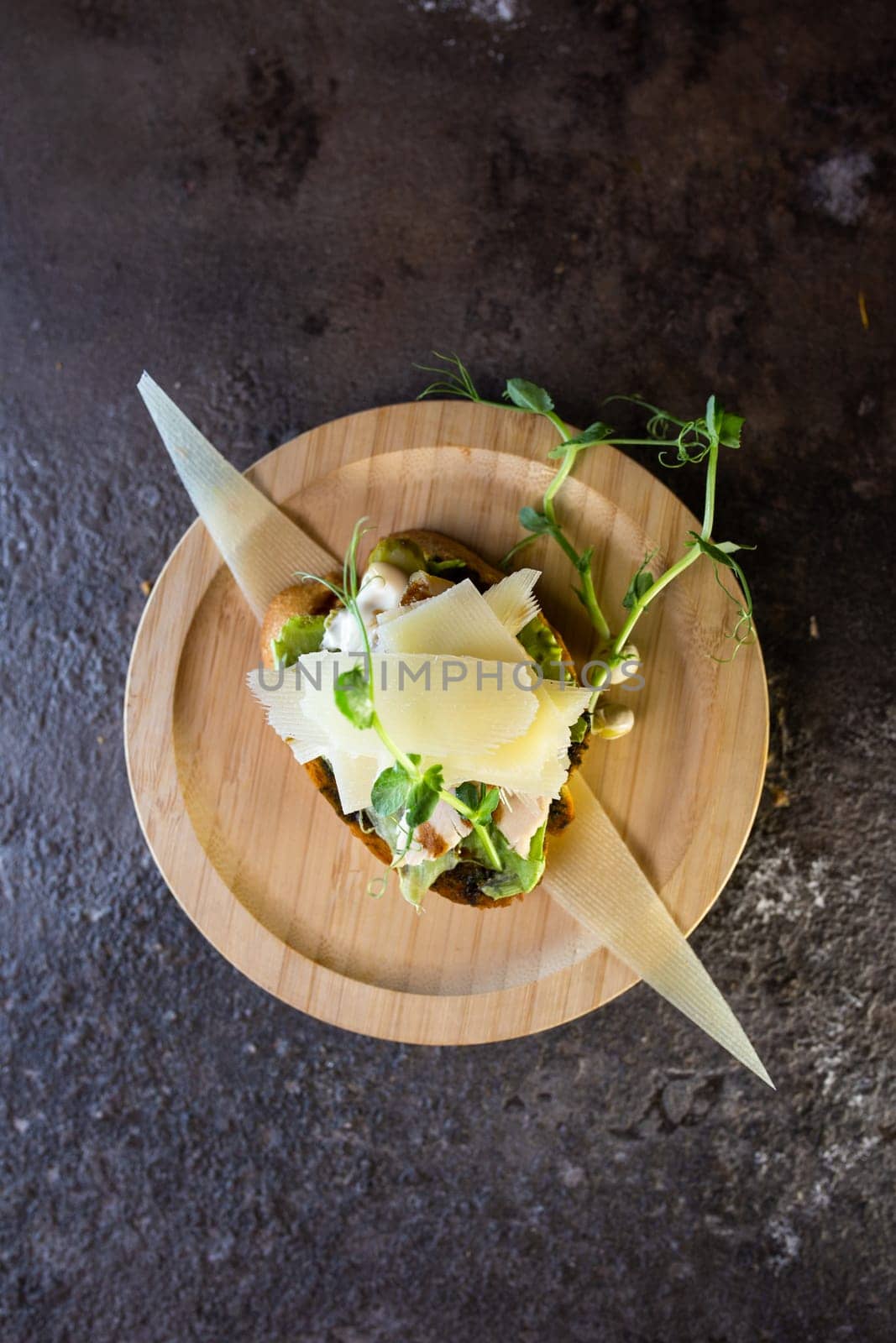 Close-up Appetizing open faced sandwich with chicken and cheese on wooden plate with dark background by Pukhovskiy