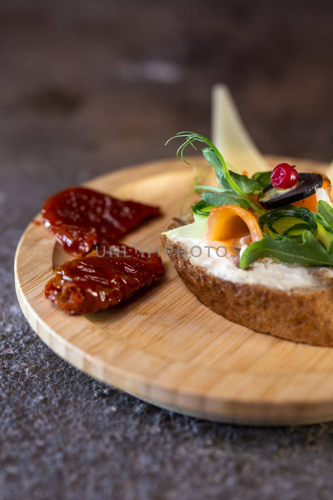 A delicious and healthy open-faced sandwich with cream cheese, smoked salmon, microgreens, and sun-dried tomato on a wooden board. Perfect for a light lunch or snack. Isolated on white background.