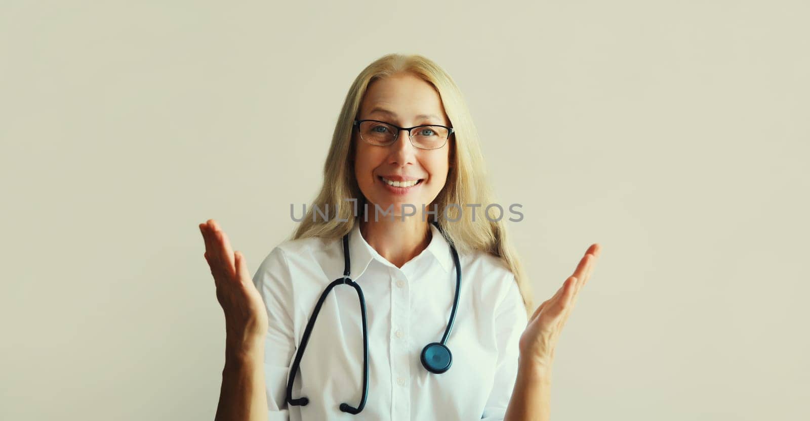 Modern caucasian middle-aged woman doctor looking at camera talking on video call sitting at desk in clinic office