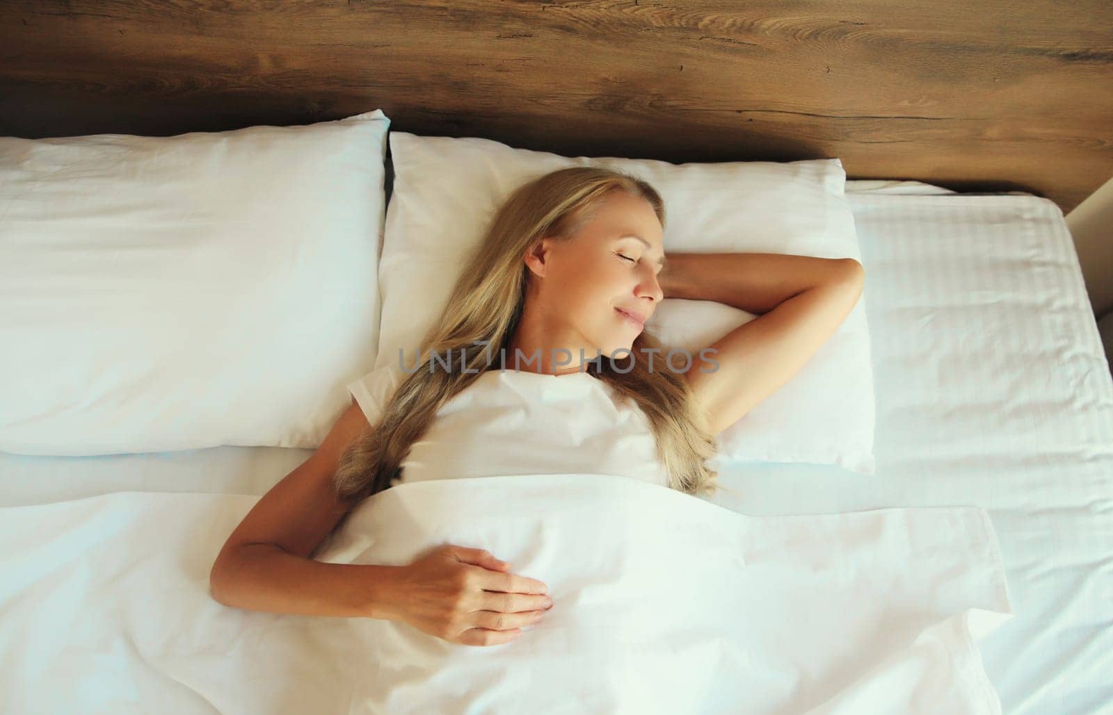 Woman sleeping lying in bed on white soft comfortable pillow in bedroom at home