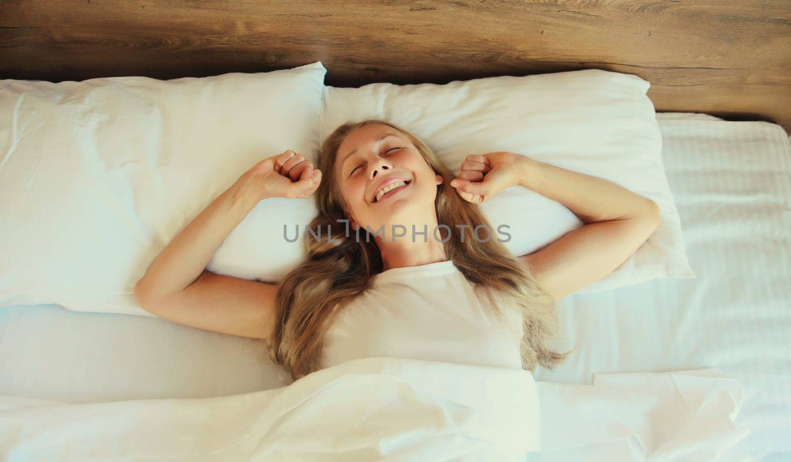 Woman sleeping lying in bed on white soft comfortable pillow in bedroom at home