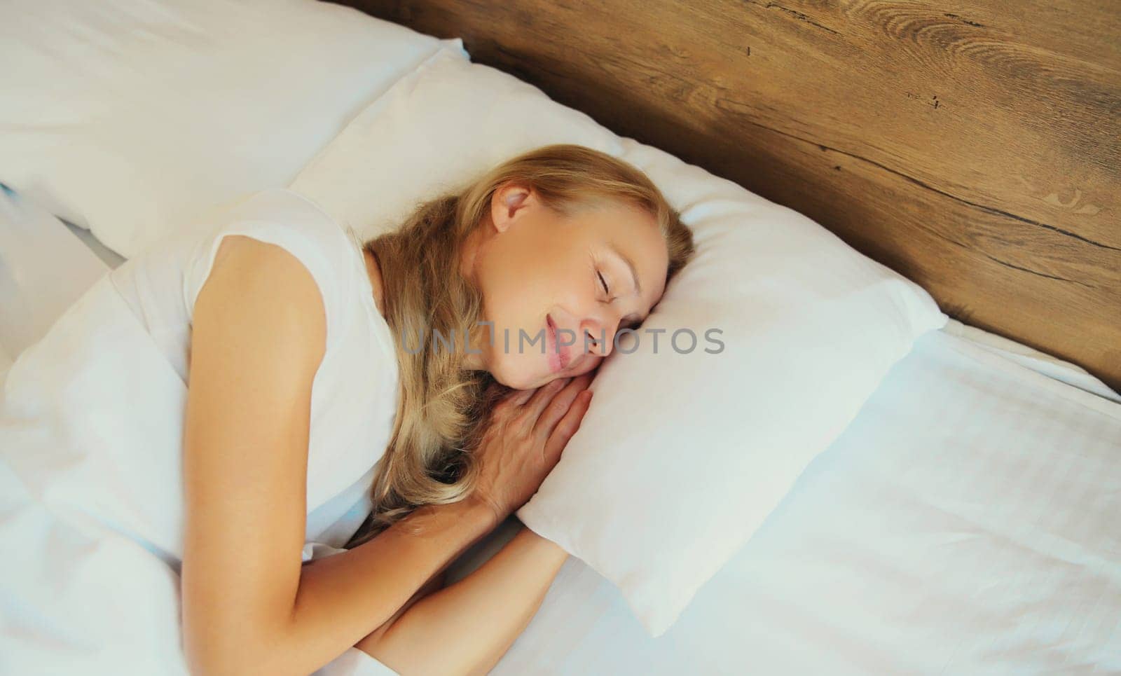 Woman sleeping lying in bed on white soft comfortable pillow in bedroom at home