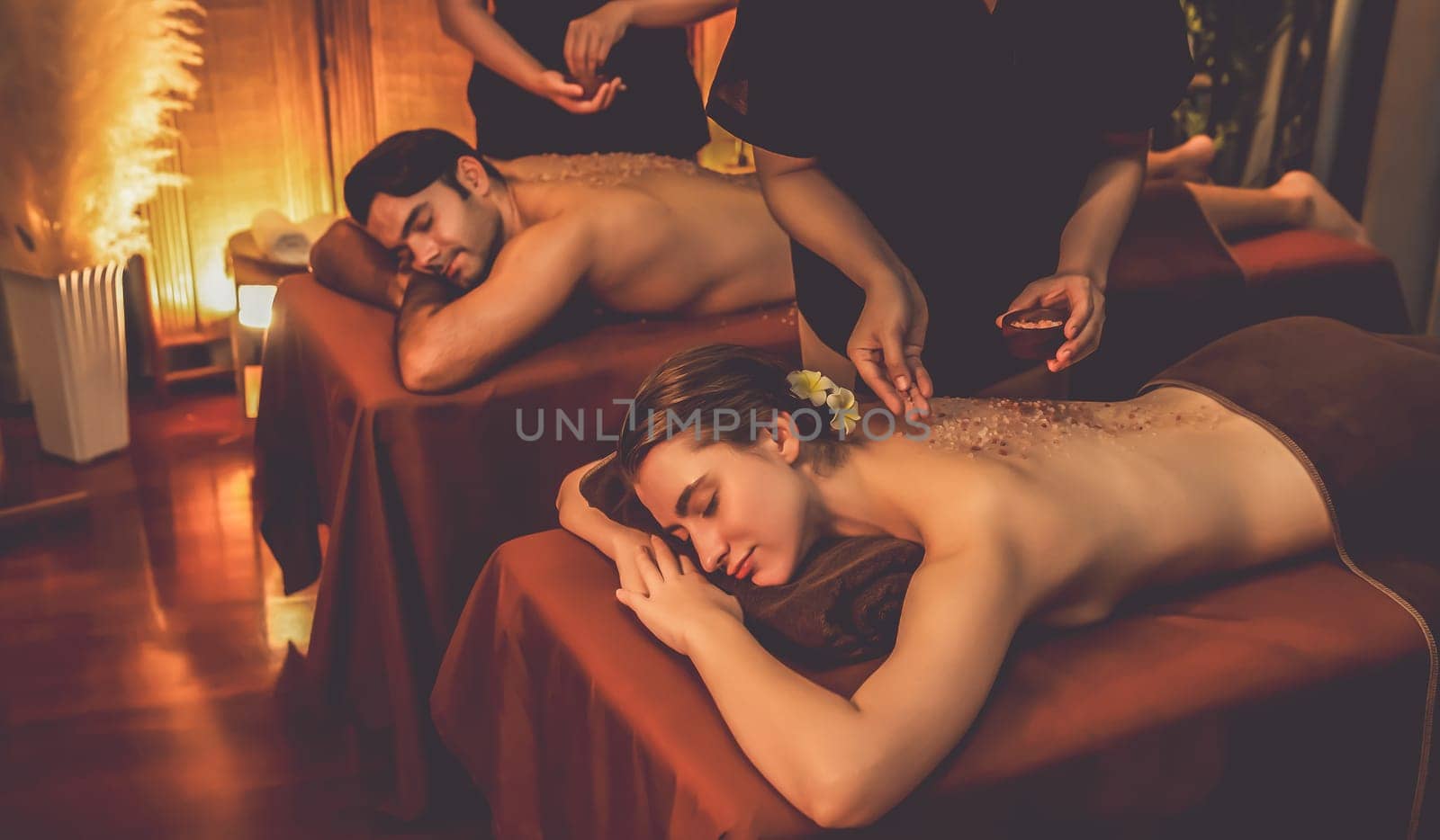 Couple customer having exfoliation treatment in luxury spa salon with warmth candle light ambient. Salt scrub beauty treatment in Health spa body scrub. Quiescent