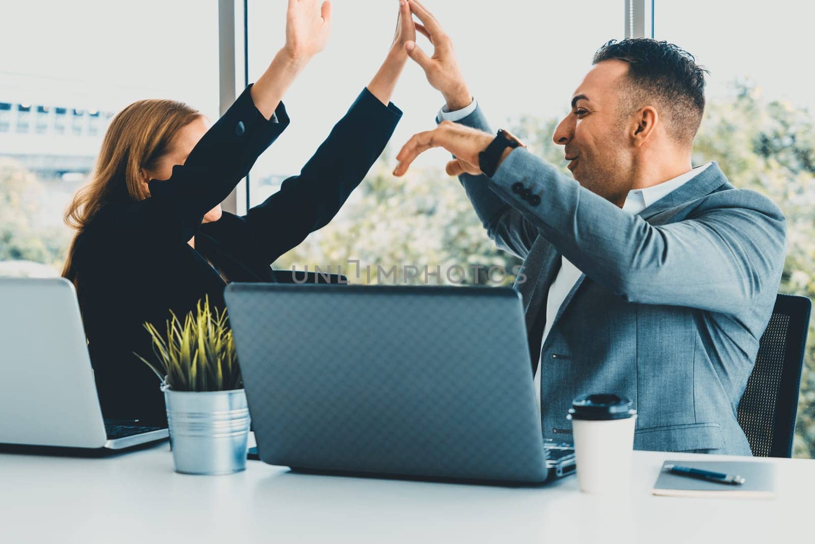 Success business partner - Businesswoman and businessman celebrating together in modern workplace office. People corporate teamwork concept. uds