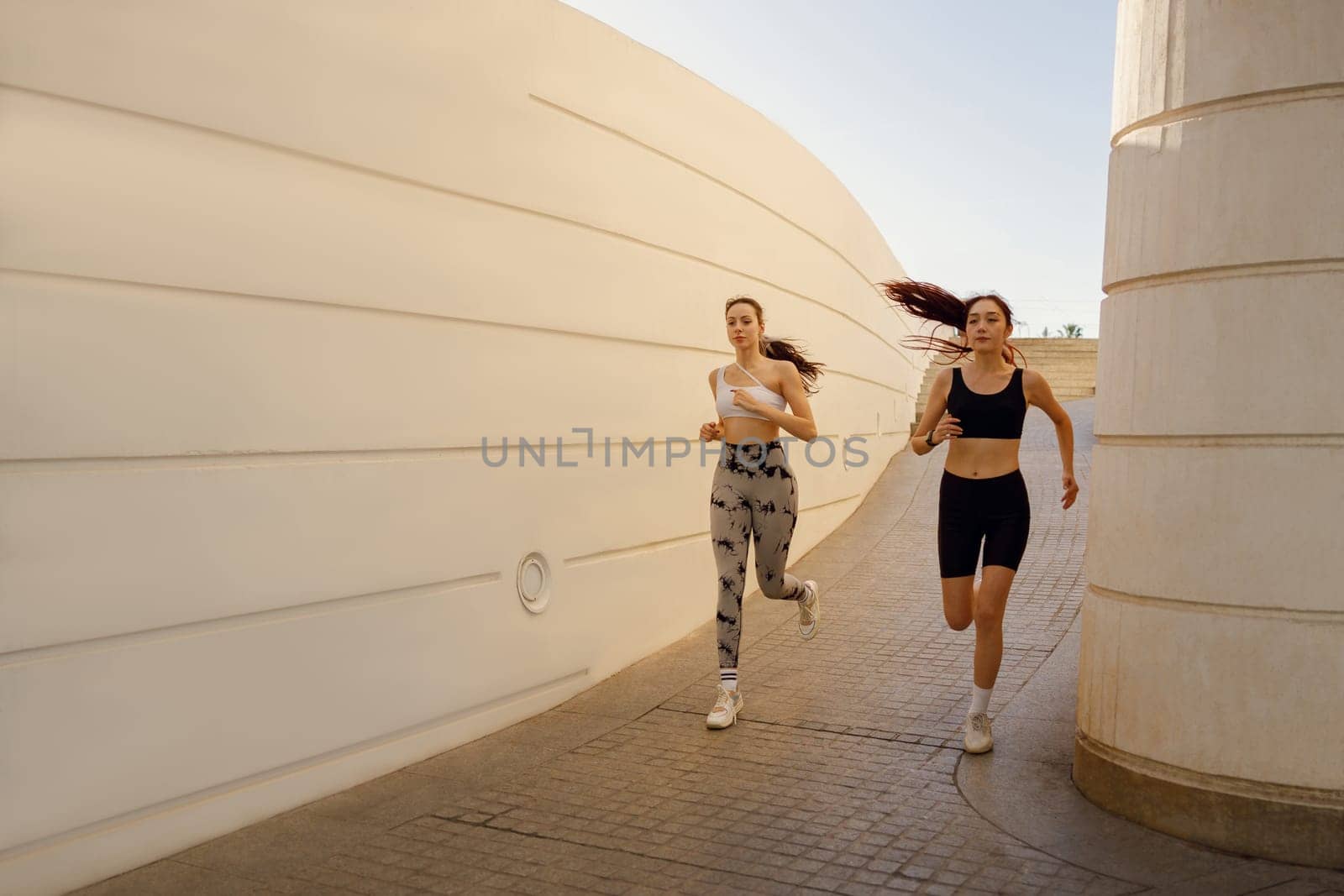 Active female friends in sportswear running outdoors on a sunny day. Morning jog