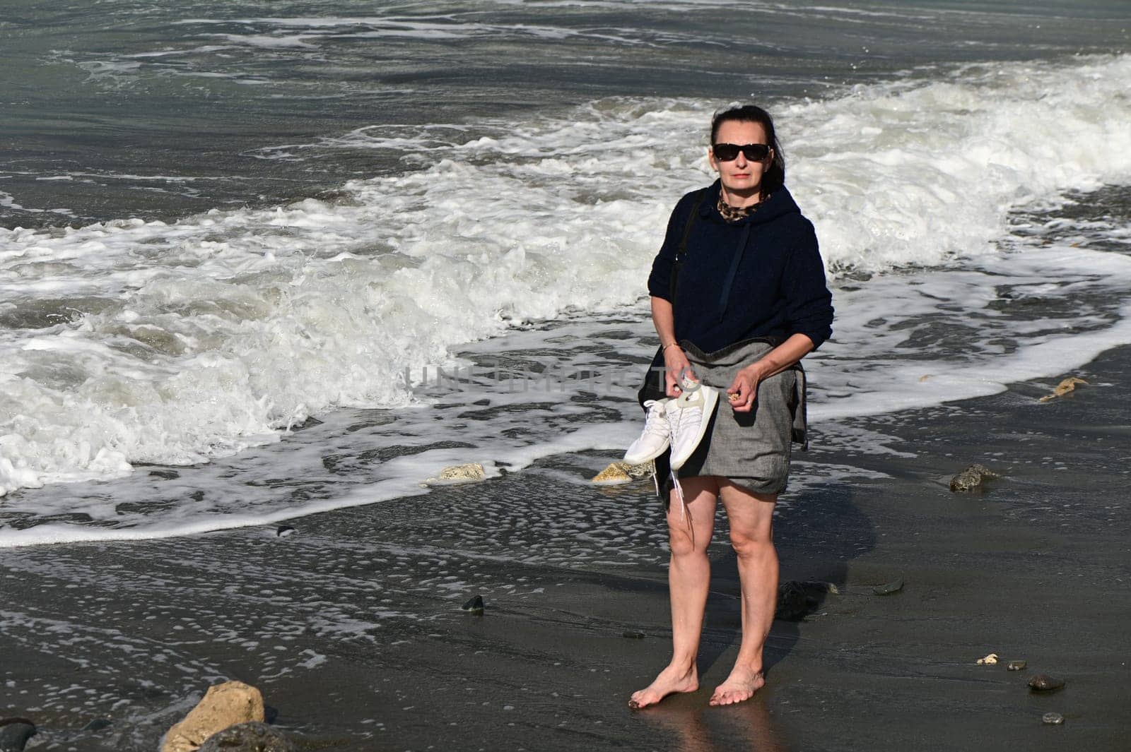 woman walks barefoot along the Mediterranean Sea in Cyprus in winter 2023 1