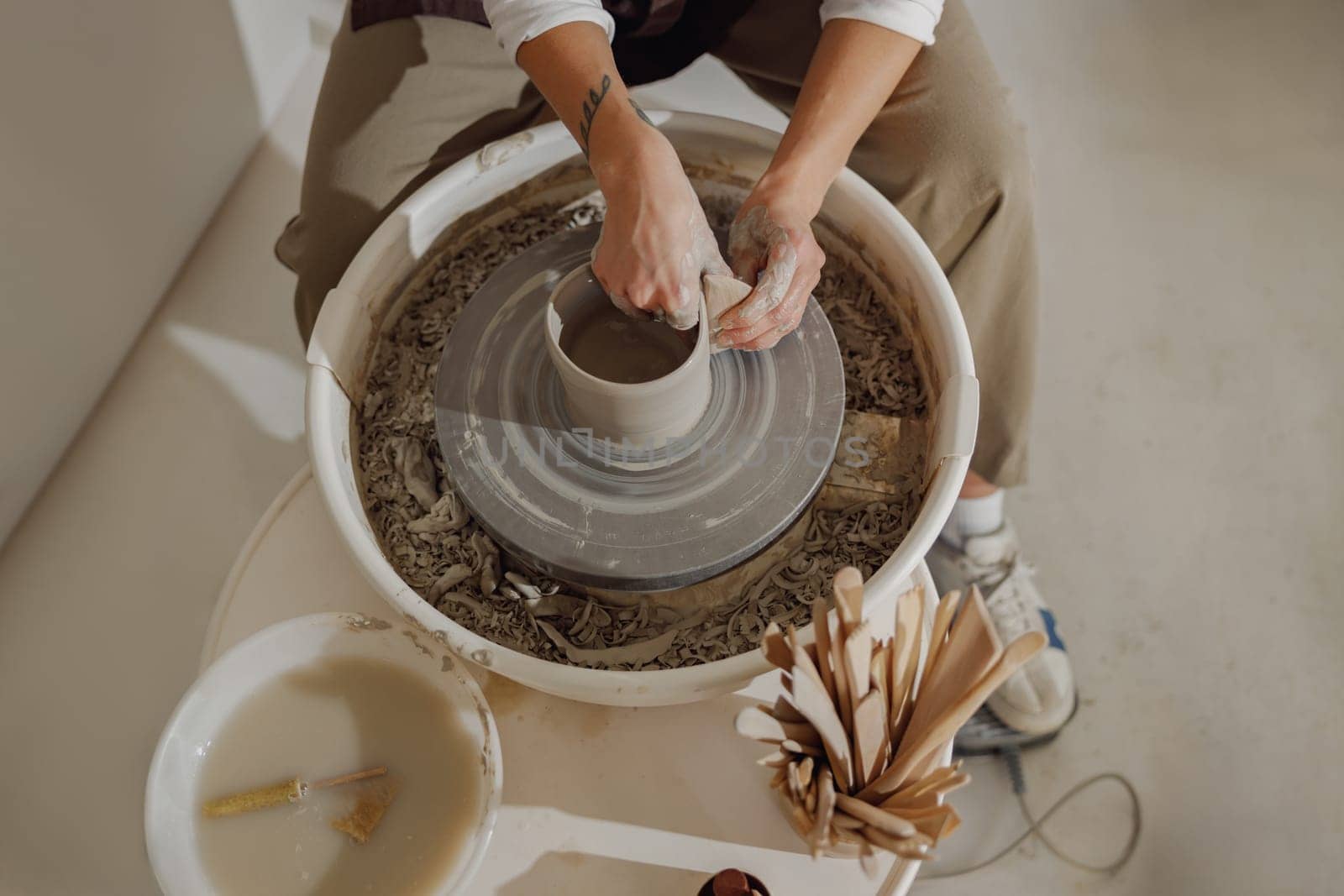 Close up of hands of professional potter molding pot shape on pottery wheel. Ceramics art concept by Yaroslav_astakhov