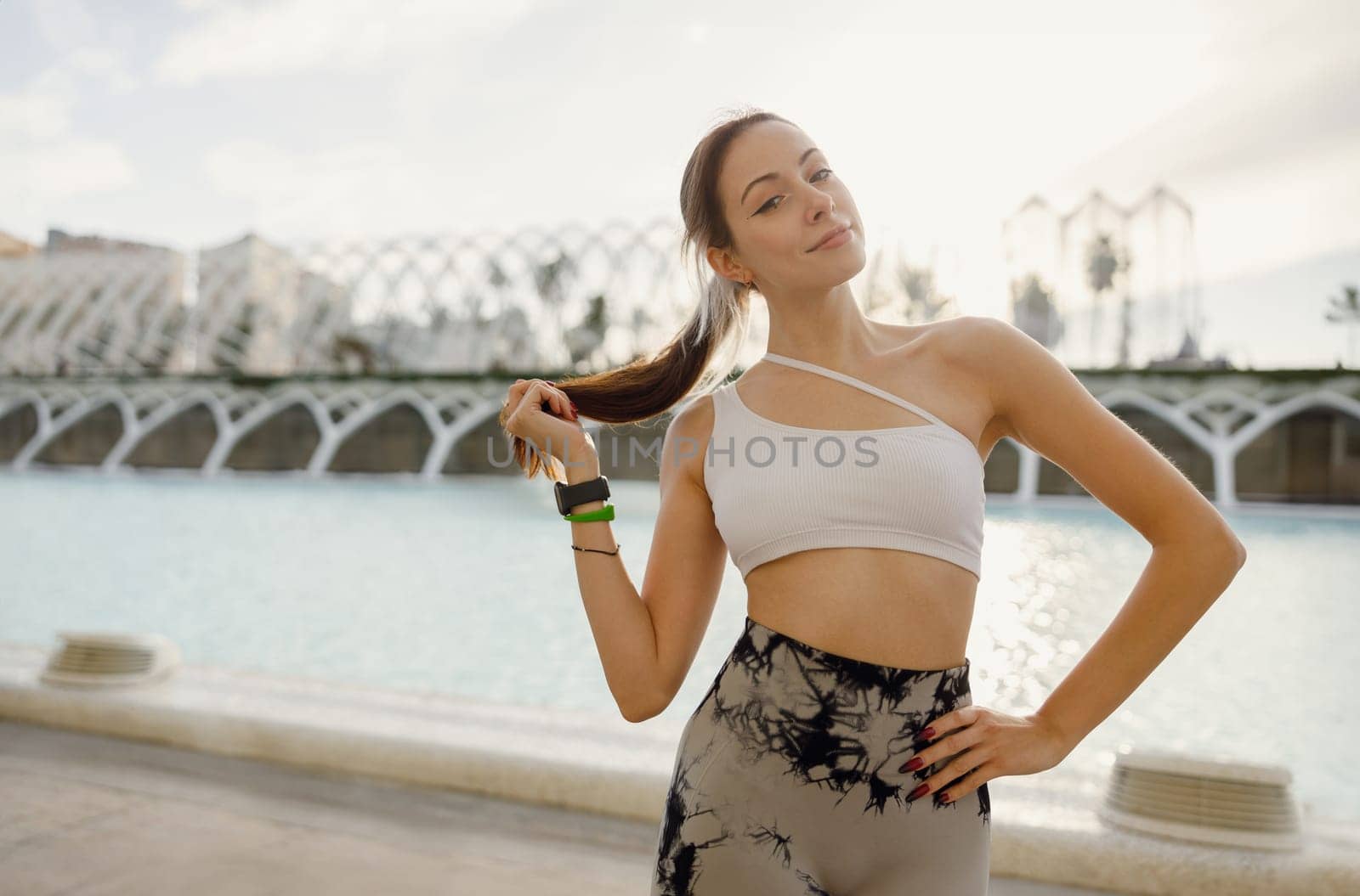 Pretty woman in sportswear have a rest after workout outside standing on building background by Yaroslav_astakhov