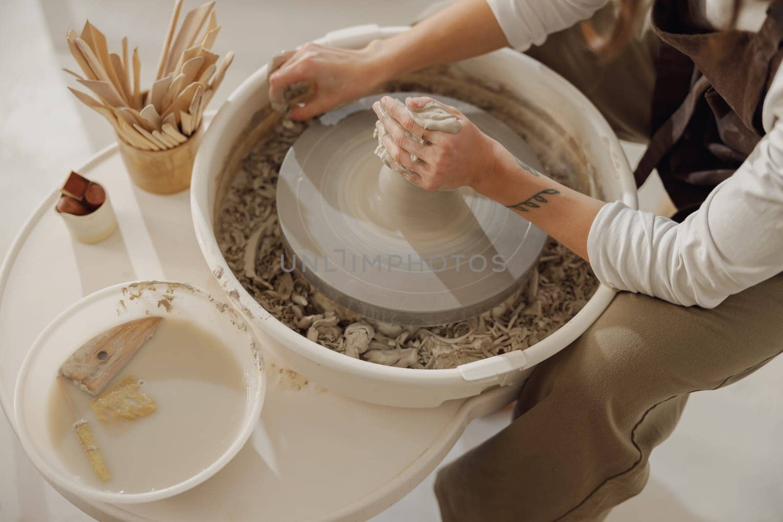Close up of hands of professional potter molding pot shape on pottery wheel. Ceramics art concept