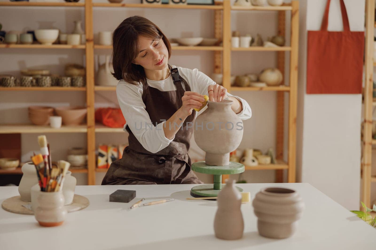 Professional female ceramist work with unfired clay vase in pottery studio. High quality photo