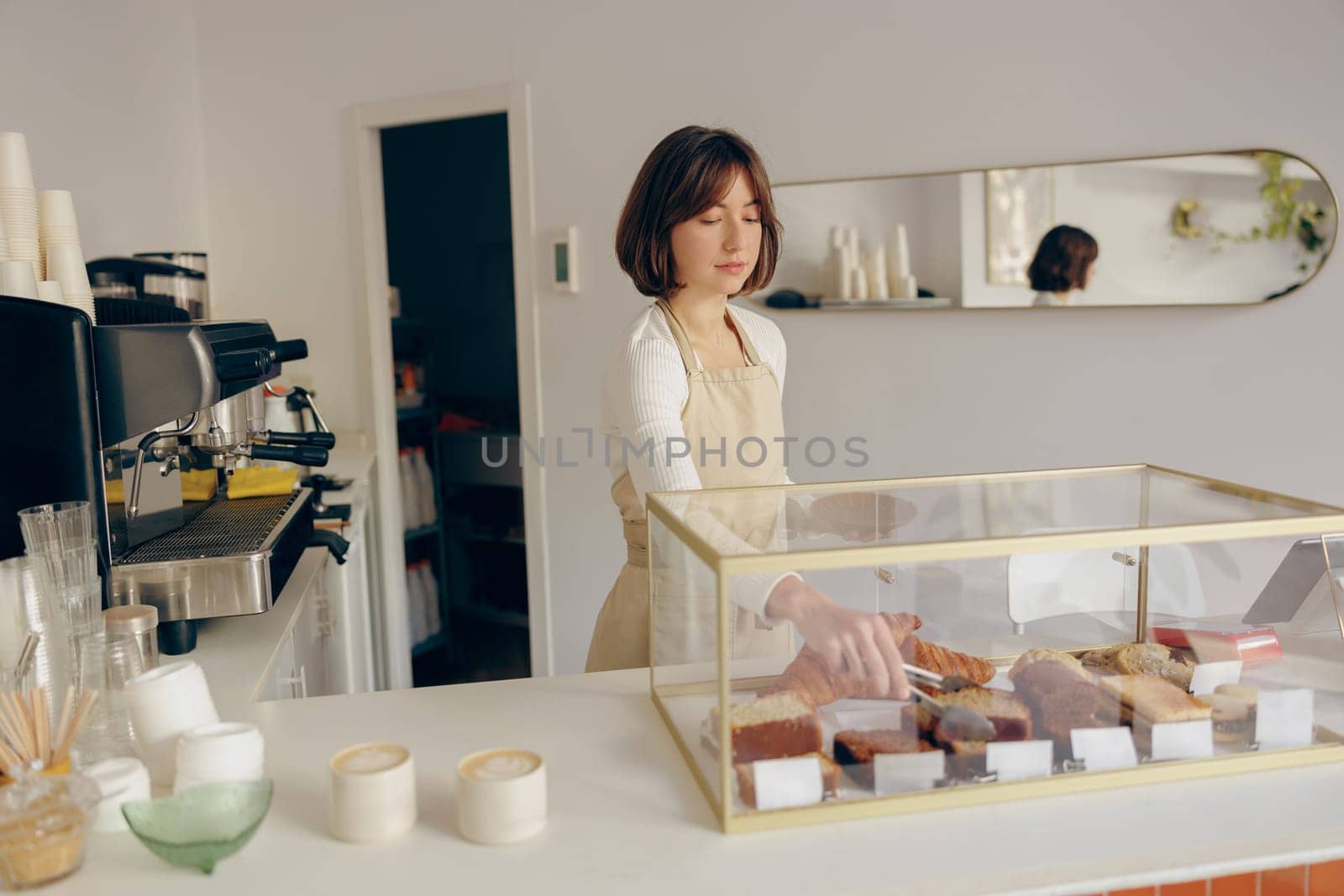 Female waitress's hand puts the piece of cupcake on the table at a cafe standing behind bar counter by Yaroslav_astakhov