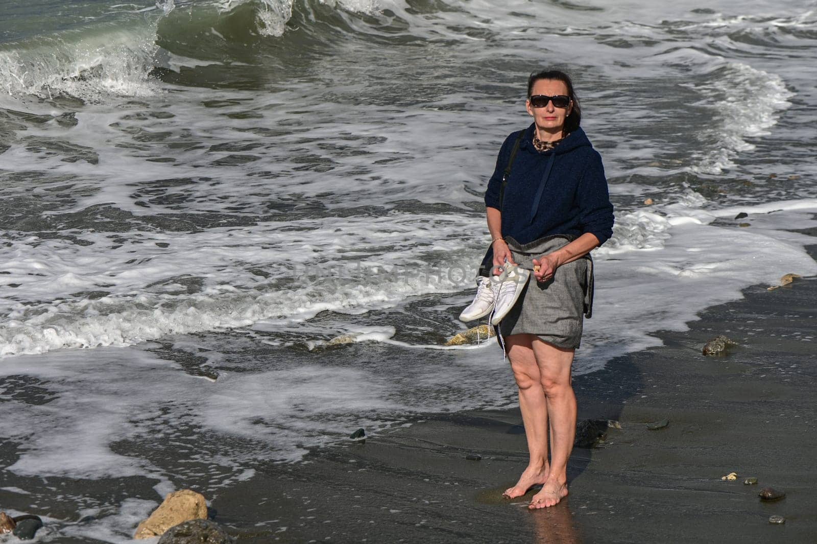 woman walks barefoot along the Mediterranean Sea in Cyprus in winter 2023 6