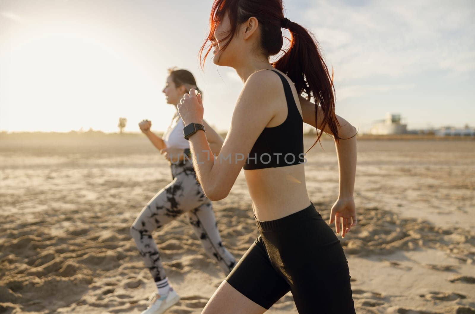 Young athletic women in sportswear is jogging along shore of beach. Concept of healthy living by Yaroslav_astakhov