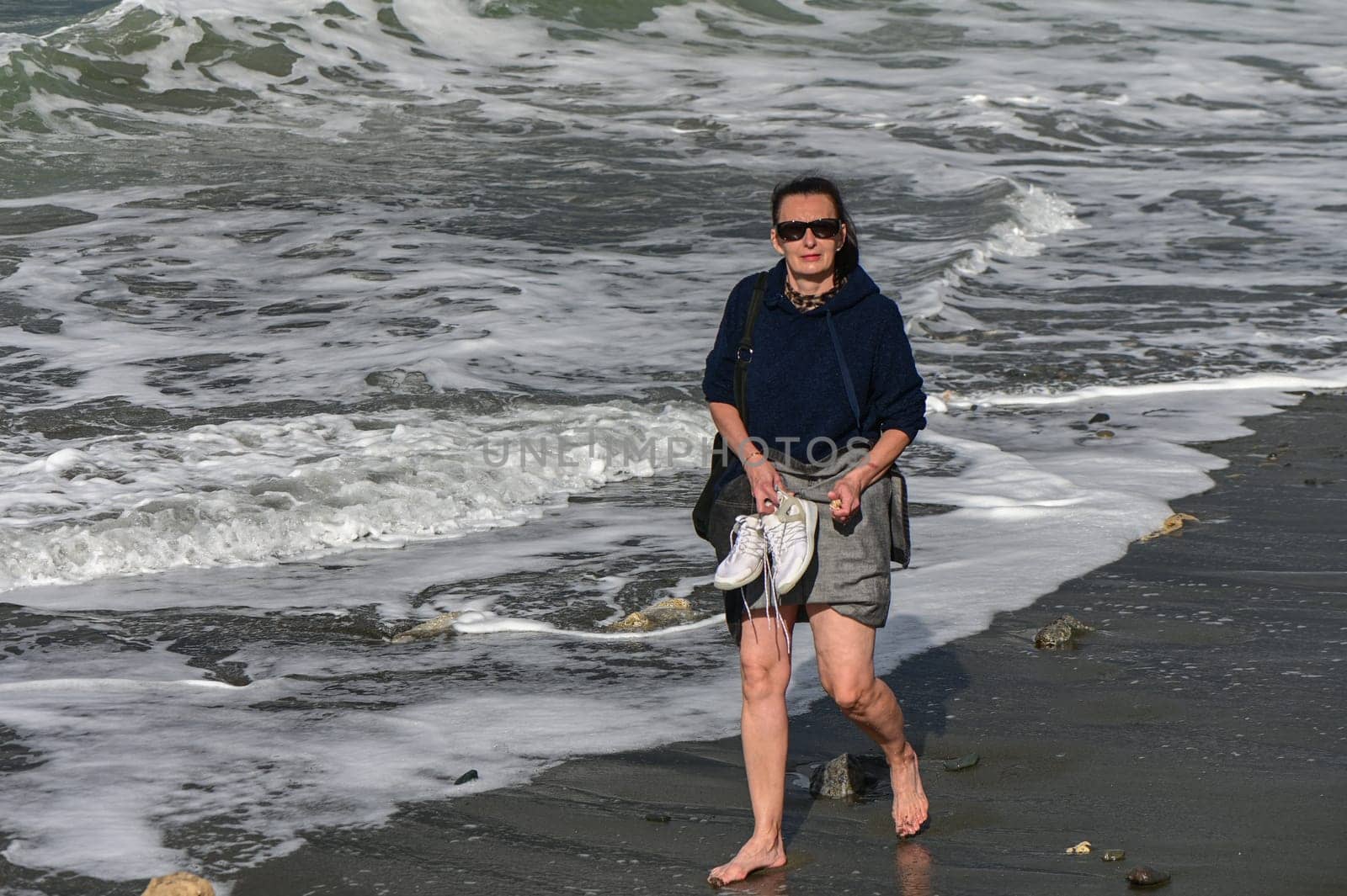 woman walks barefoot along the Mediterranean Sea in Cyprus in winter 2023 7