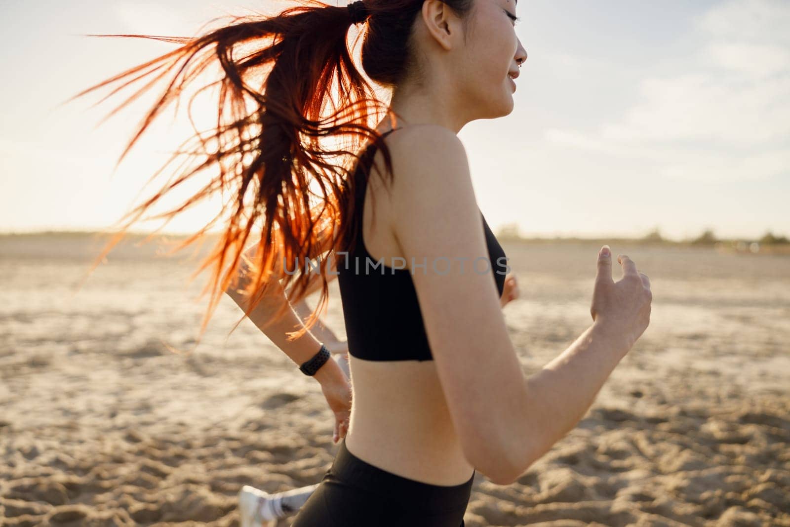 Close up of athletic women in sportswear is jogging along shore of beach. Concept of healthy living by Yaroslav_astakhov