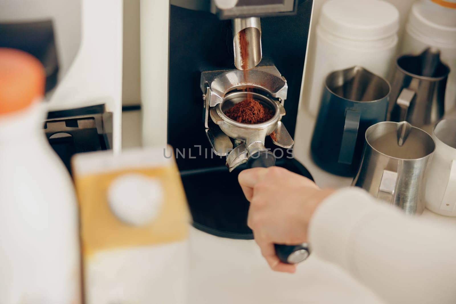 Close up of female barista grind coffee bean with grinder machine while working in cafe