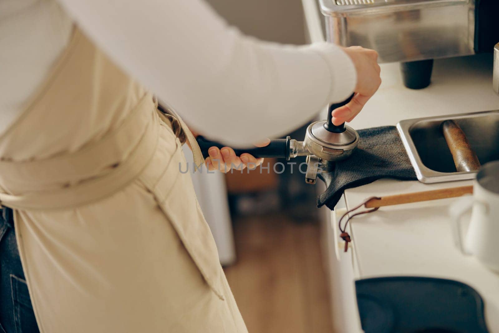 Close-up of barista using a tamper to press ground coffee into a portafilter at the coffee shop by Yaroslav_astakhov