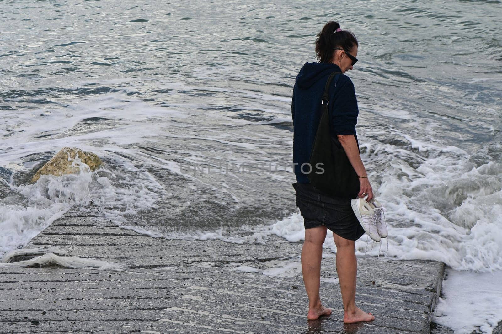 woman walks on the waves of the Mediterranean Sea in Cyprus in winter 2023 1 by Mixa74