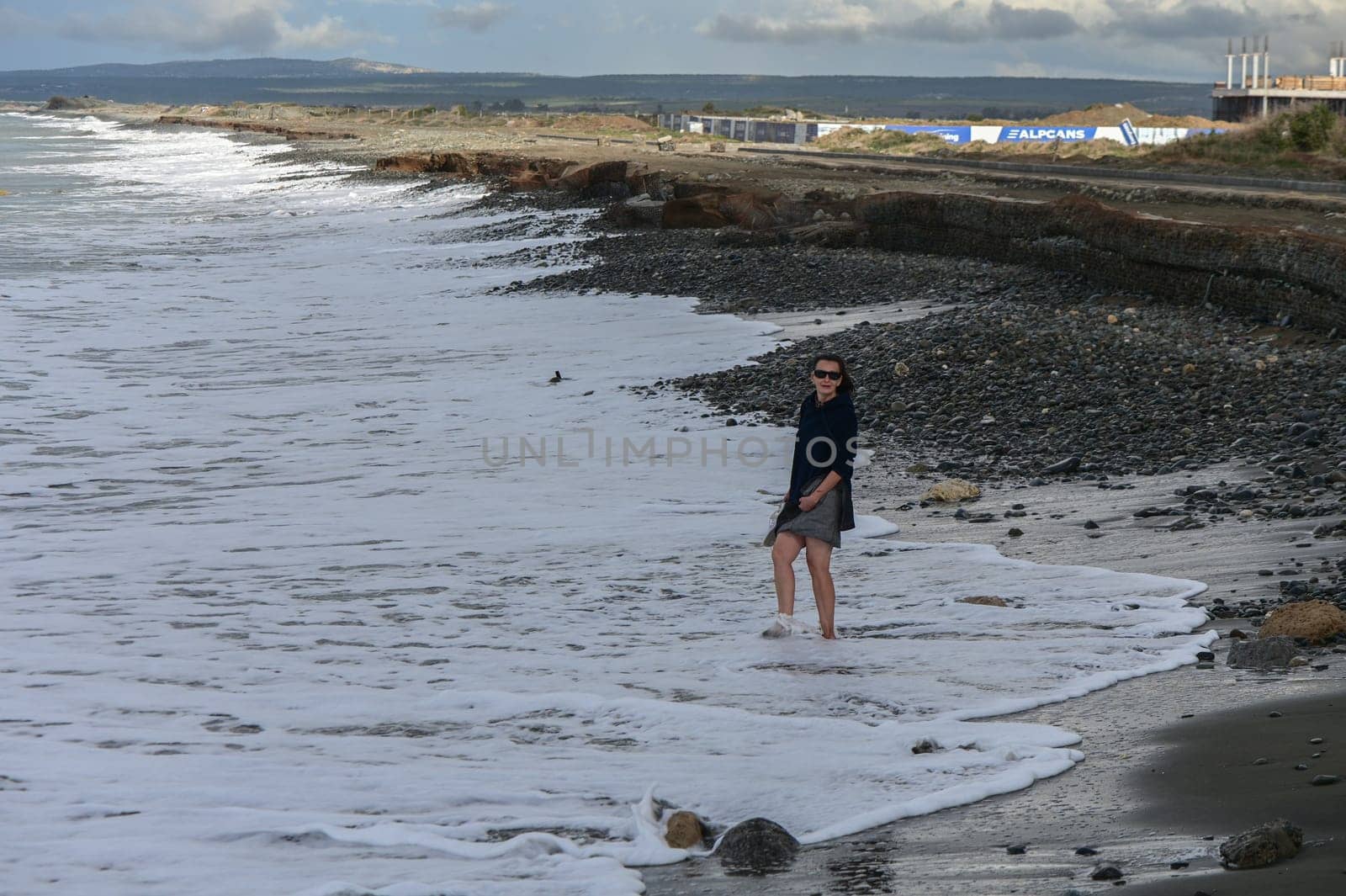 woman walking barefoot on the beach of the Mediterranean Sea in Cyprus in winter 2 by Mixa74