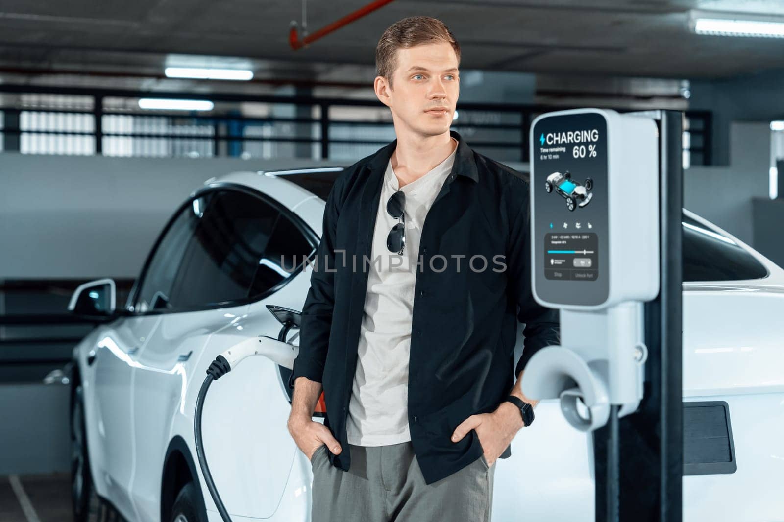 Young man travel with EV electric car to shopping center parking lot innards by biancoblue