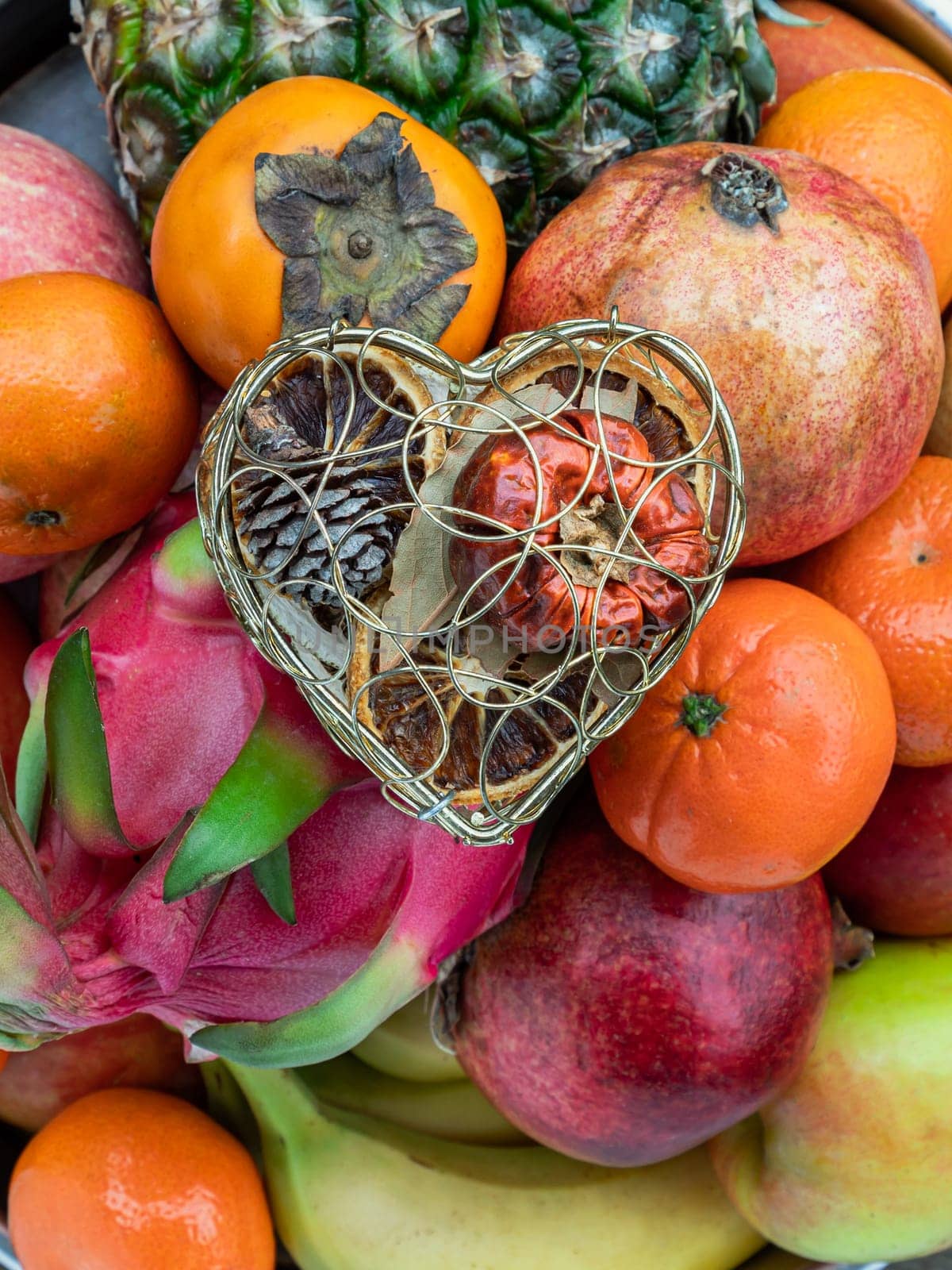 Golden heart shaped mesh case is filled with Dried fruits on Variety of assorted fruits. Colorful love concept, Space for text, Selective focus.