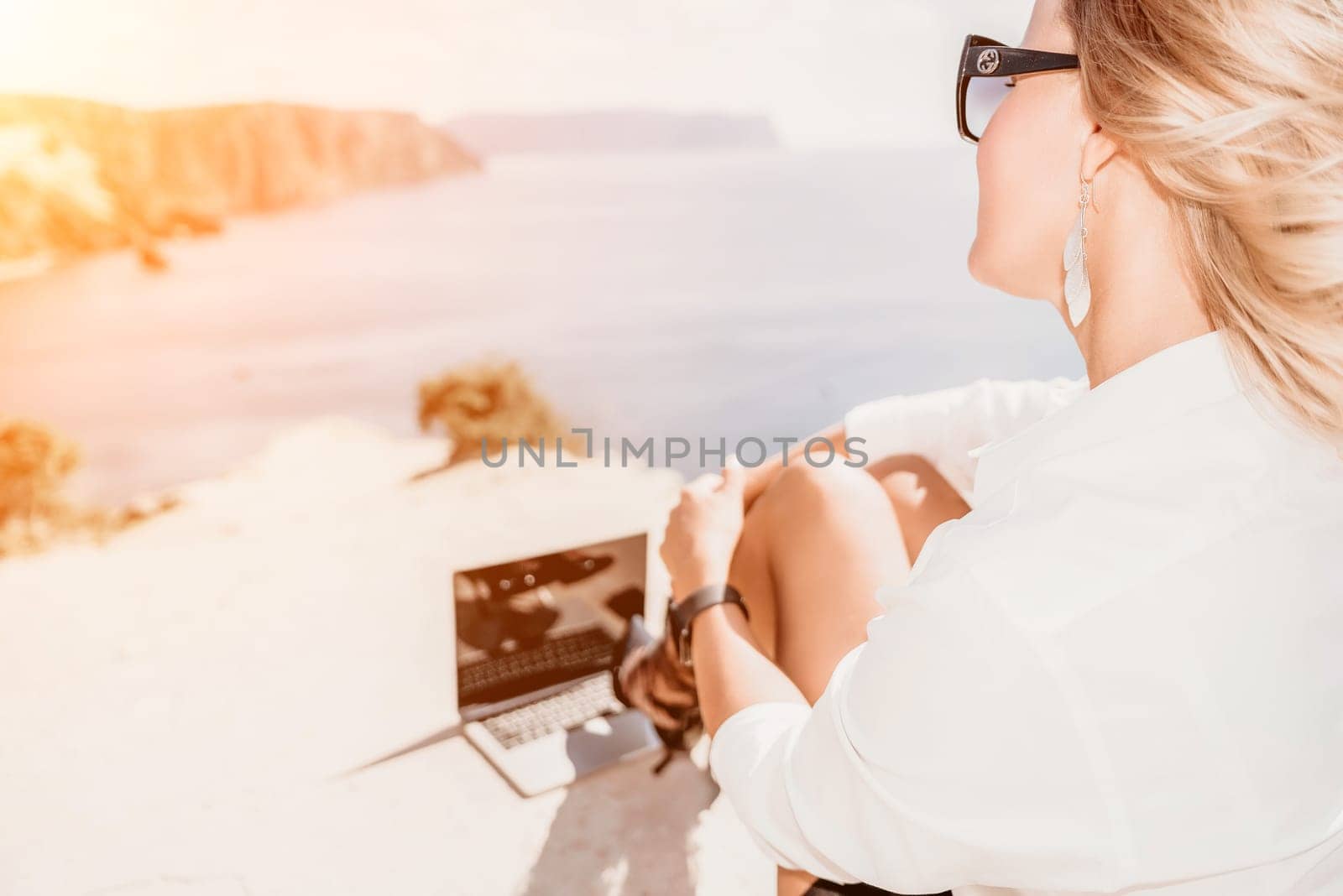 Happy girl doing yoga with laptop working at the beach. beautiful and calm business woman sitting with a laptop in a summer cafe in the lotus position meditating and relaxing. freelance girl remote work beach paradise