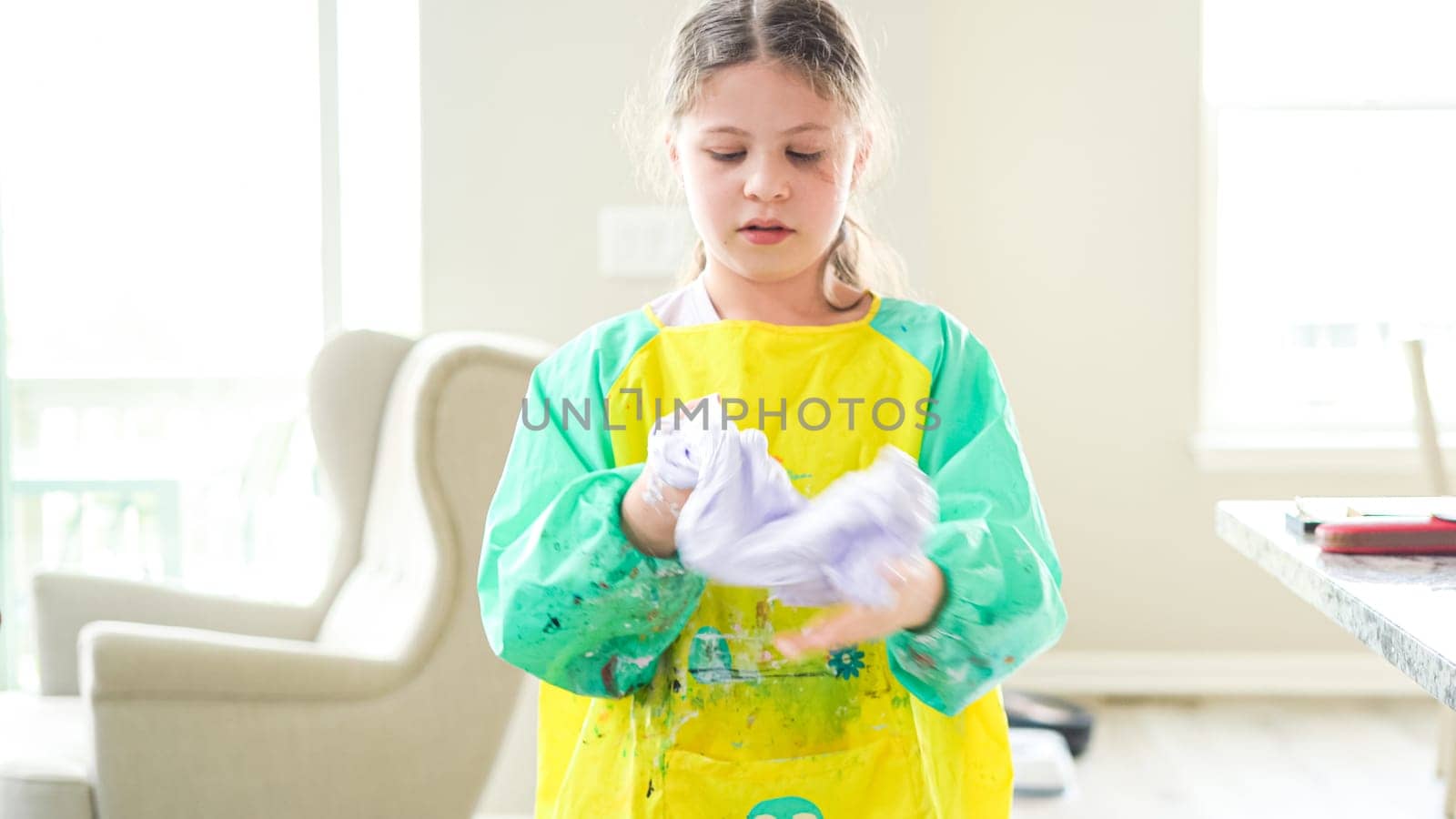 In a modern kitchen, a homeschooled girl is engrossed in creating homemade slime, a fun and educational hands-on project that enhances her creativity and problem-solving skills.