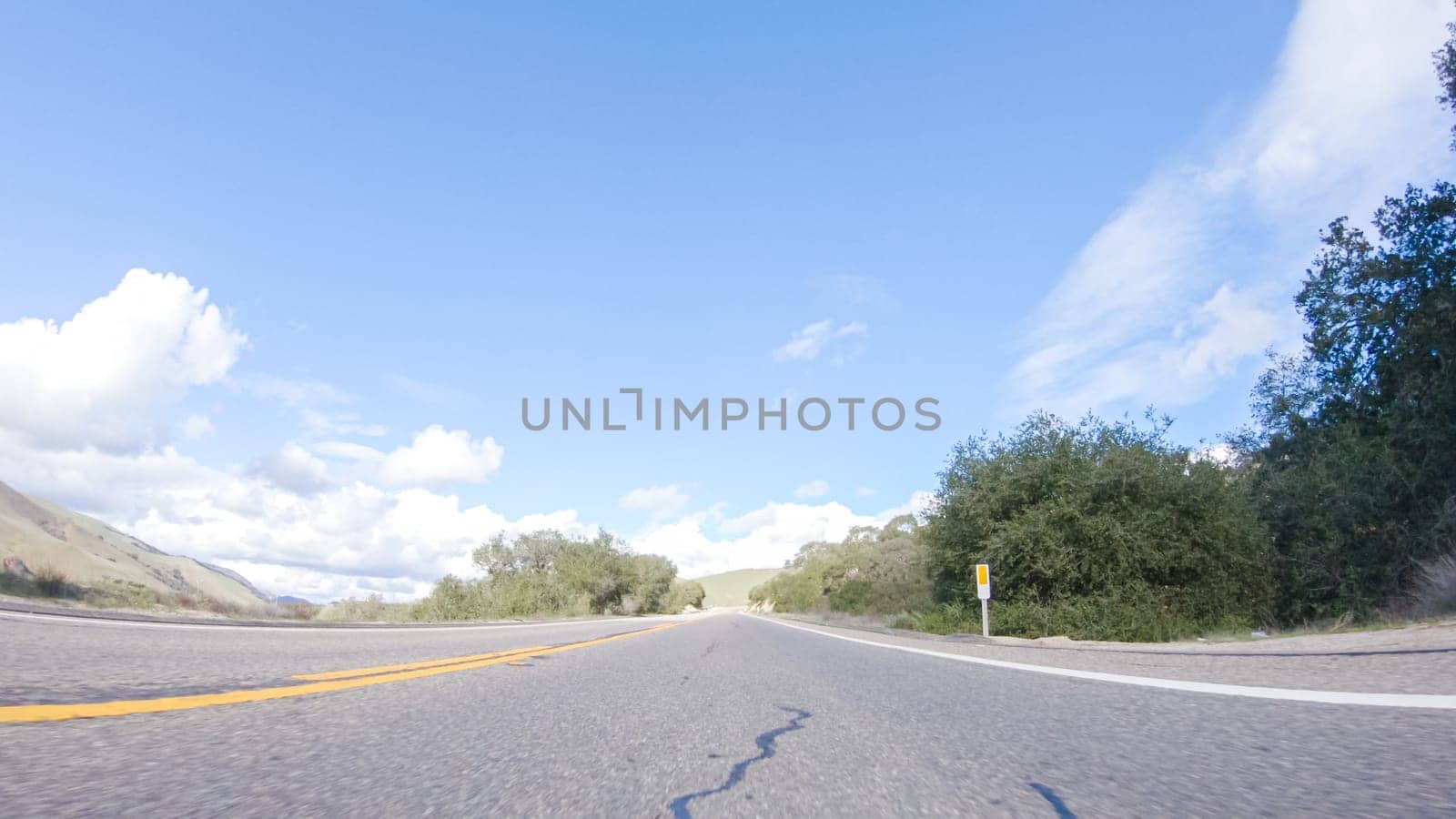 Vehicle is cruising along the Cuyama Highway under the bright sun. The surrounding landscape is illuminated by the radiant sunshine, creating a picturesque and inviting scene as the car travels through this captivating area.