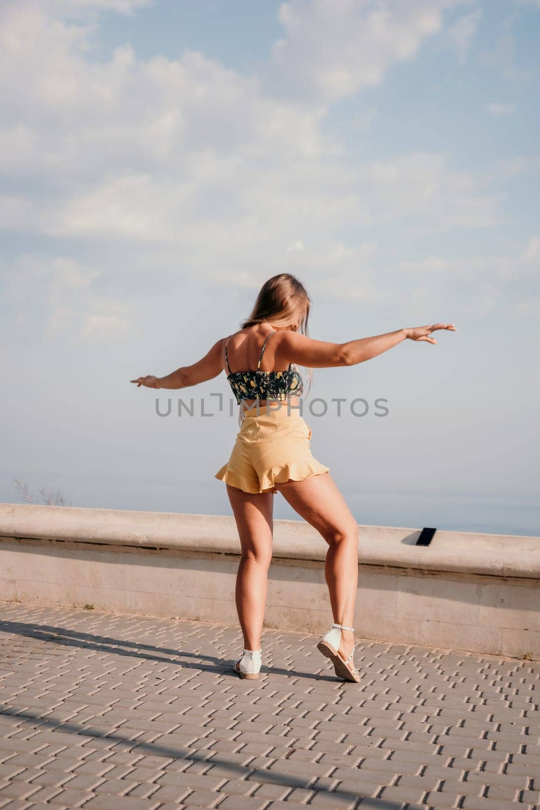 silhouette of a happy woman who dances, spins and raises her hands to the sky. A woman is enjoying a beautiful summer day.