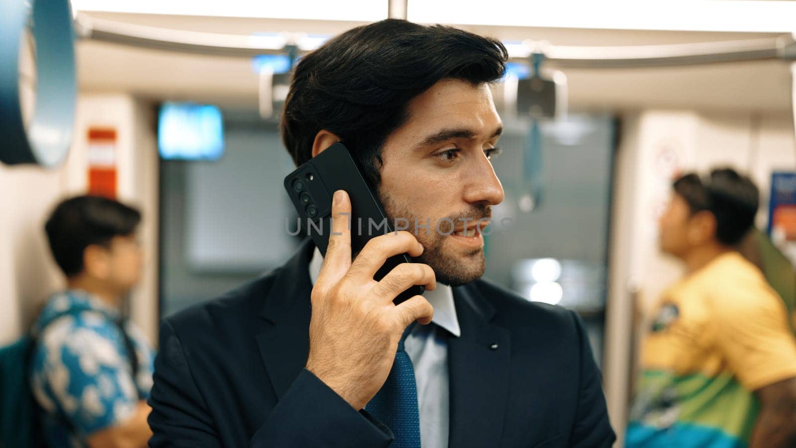 Smart business man phone calling to project manager while standing in train. Professional male leader talking to investor about marketing plan by using phone with blurring background. Exultant.