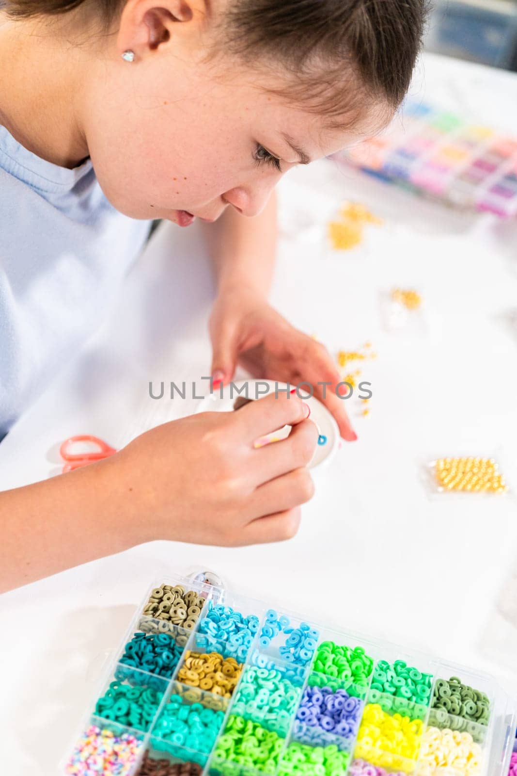 Little girl enjoys crafting colorful bracelets with vibrant clay beads set.