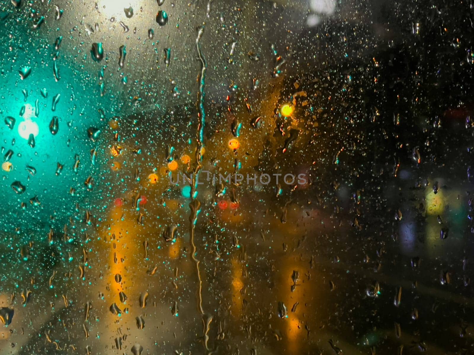 Rain bokeh road lights. Abstract shot of evening city traffic bokeh. Multicolored lights of the evening city and passing cars through a wet rainy window. by Matiunina