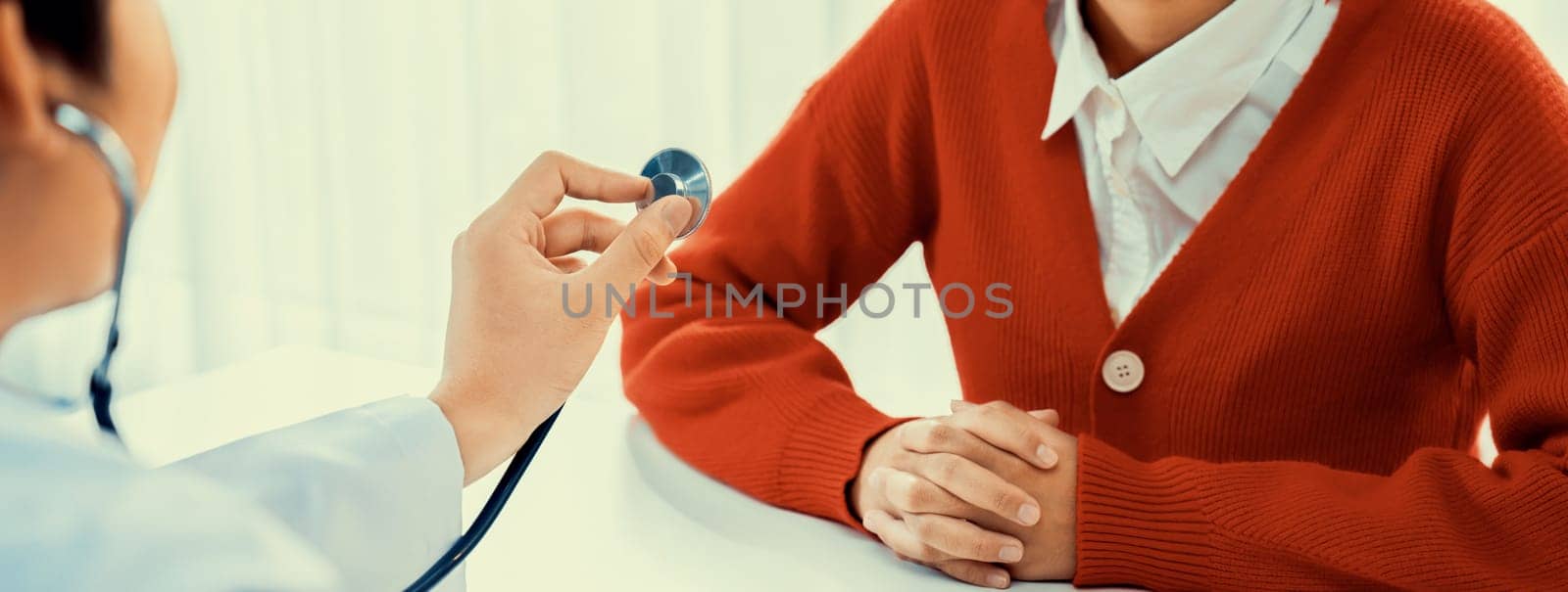 Patient attend doctor's appointment at clinic or hospital office. Doctor examining and diagnosis symptoms while checking the patient's pulse with stethoscope. Panorama Rigid