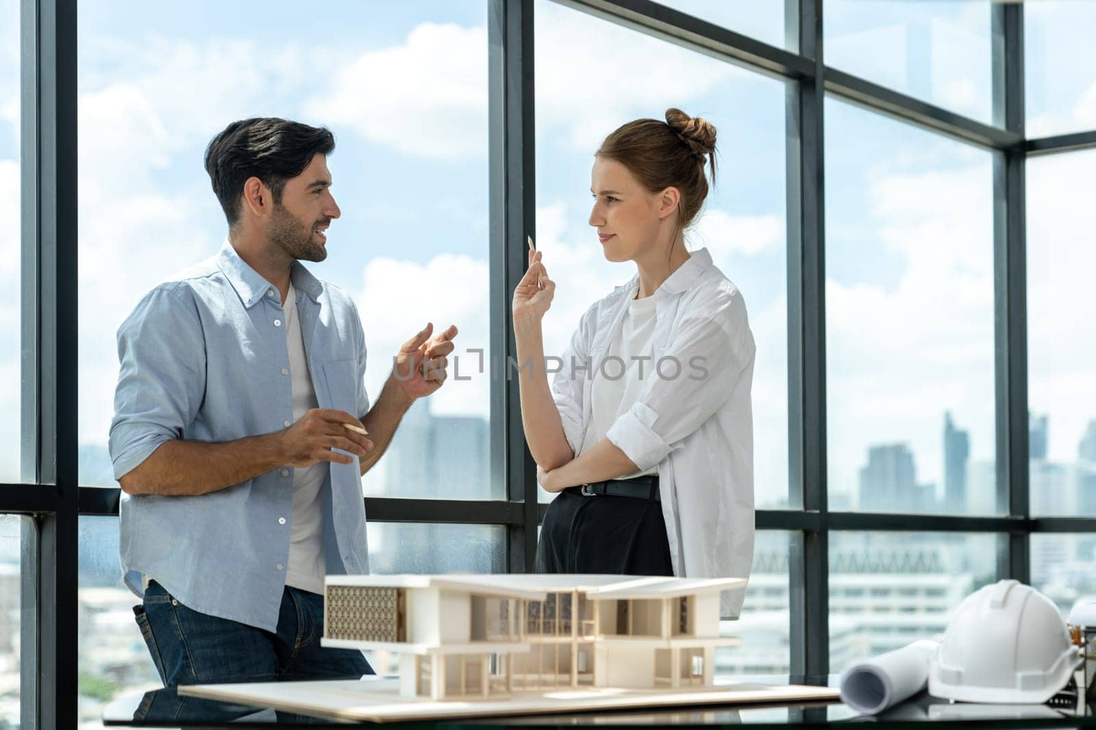 Professional architect engineer team discussing about house construction. Expert businesspeople sharing and brainstorming idea about house design. Working together. Skyscraper. Tracery.