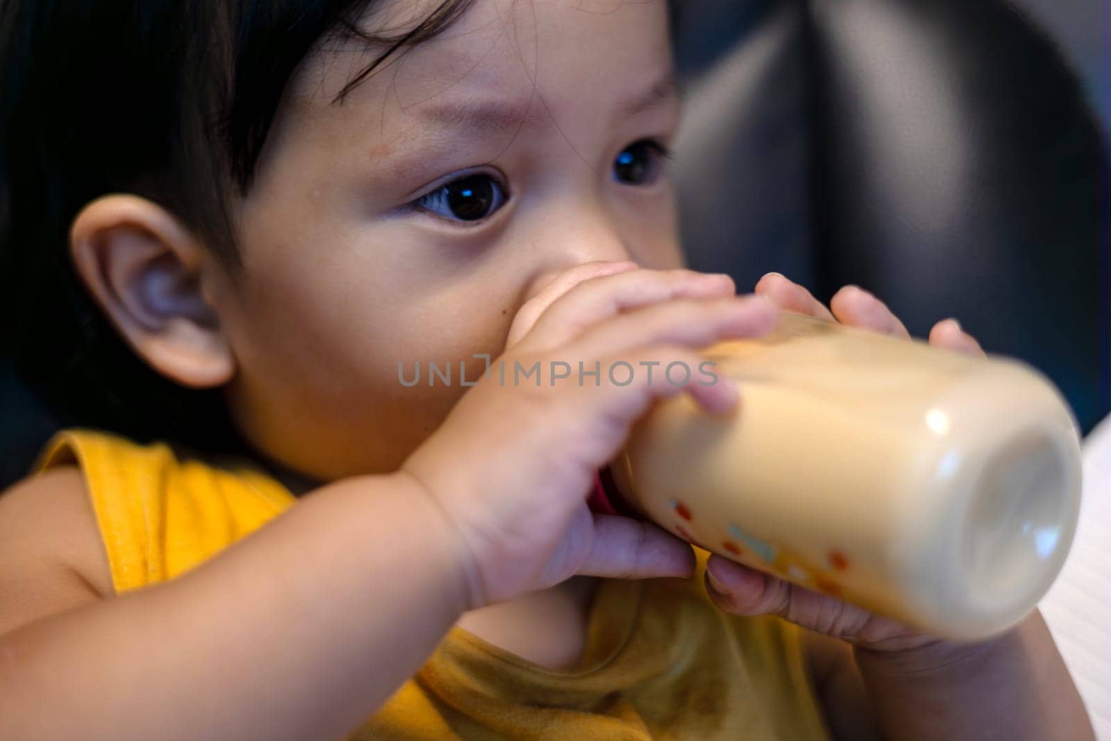 Adorable baby boy  drinking milk from a bottle. Formula drink for infant.