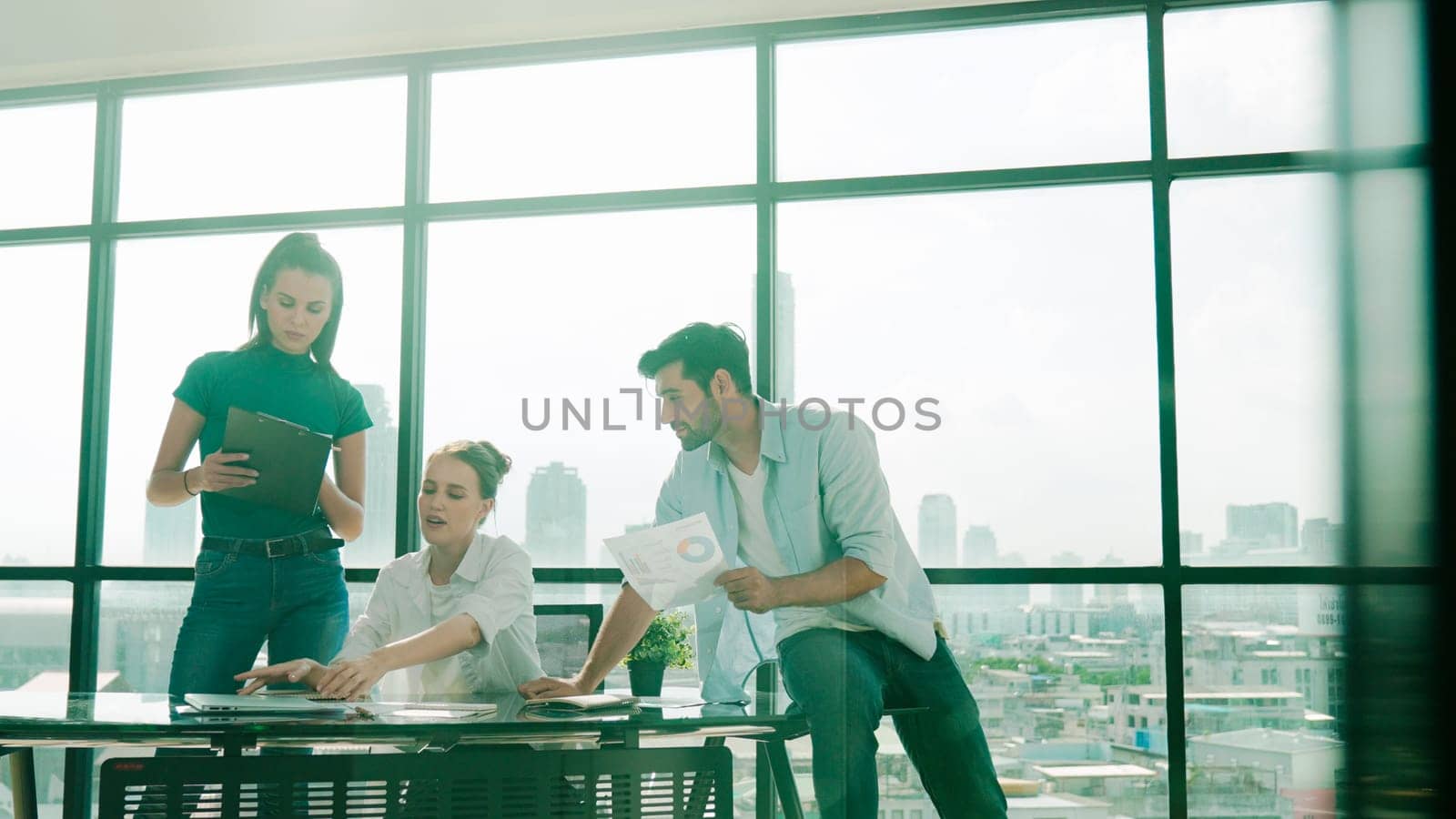 Group of happy skilled businesspeople discuss, brainstorming, sharing idea, plan, strategy about financial statistic on meeting table with laptop and statistic document. Cityscape view. Tracery