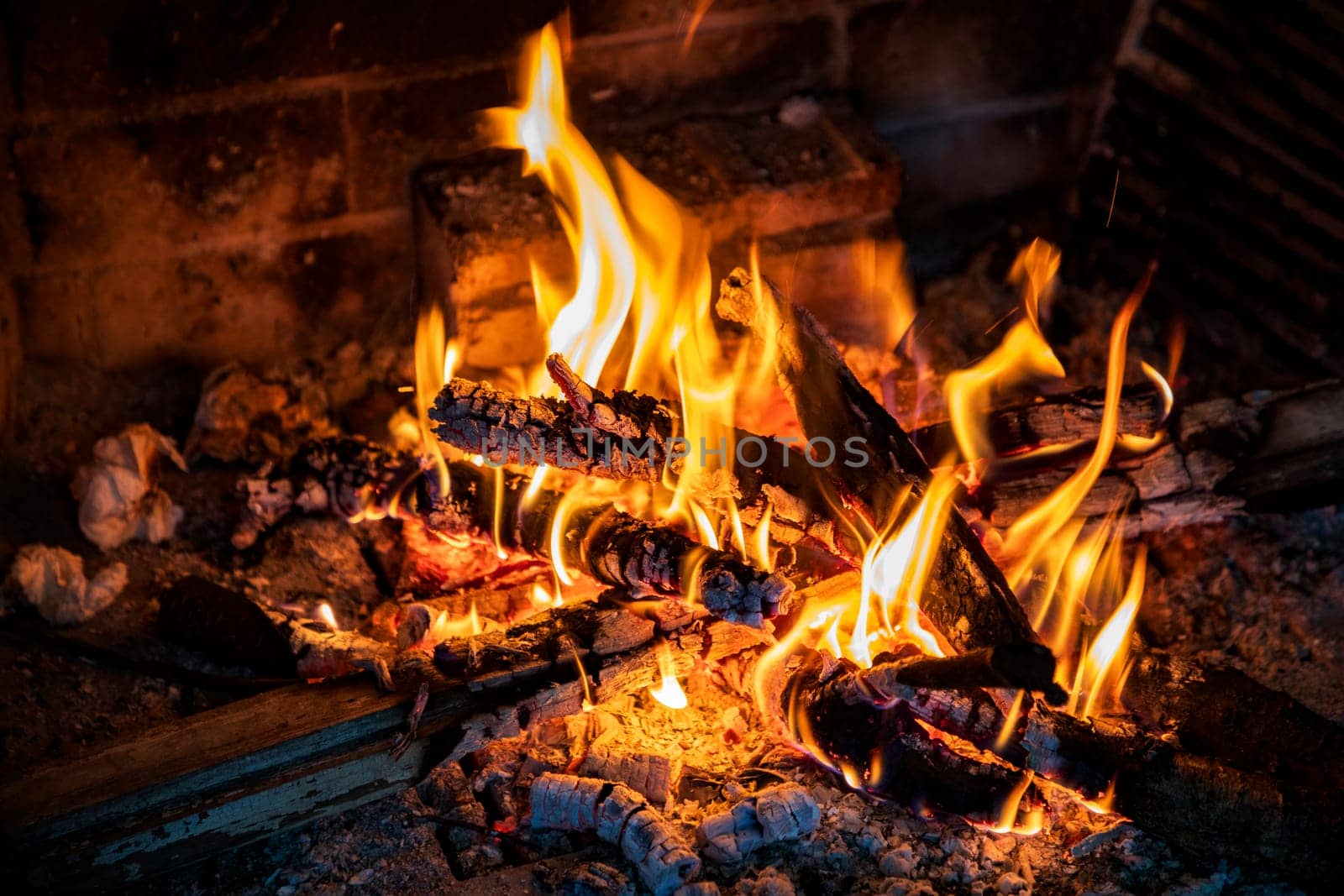 Burning firewood in a fireplace, vivid burning orange and yellow flames.