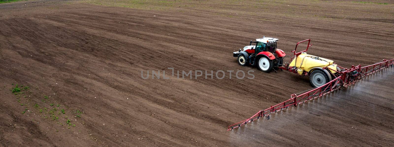 Banner view of field and tractor spraying grain by EdVal