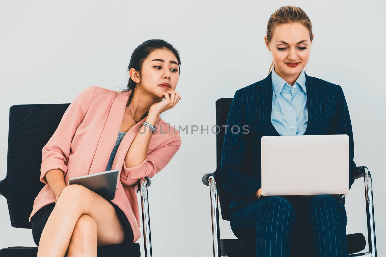 Curious businesswoman looking at the screen of laptop computer of another businesswoman spying stealing idea and copying private information from coworker at workplace. Plagiarism concept. uds